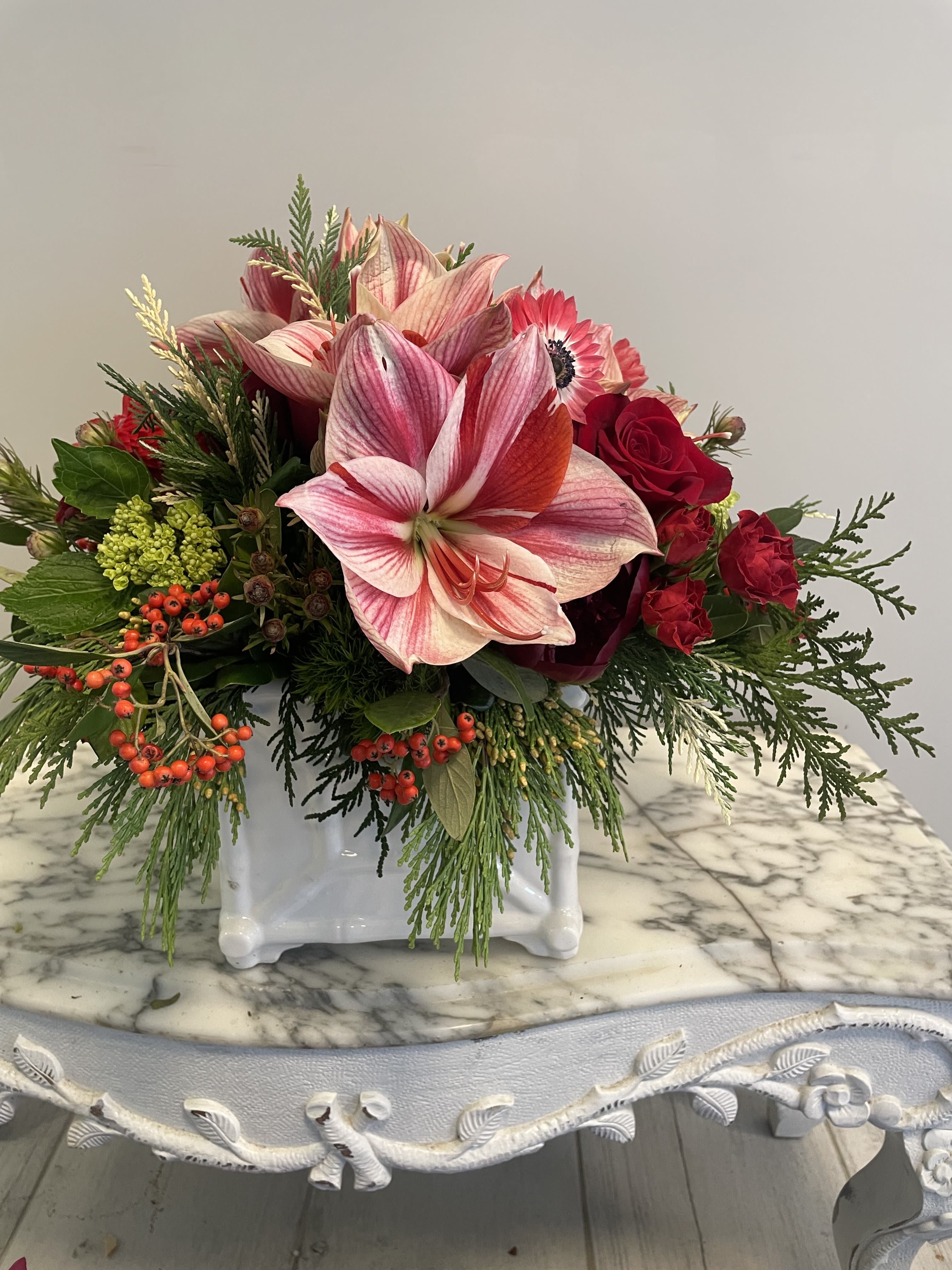 Jingle Belle - Anemone, Amaryllis, berries in shades of red with evergreens