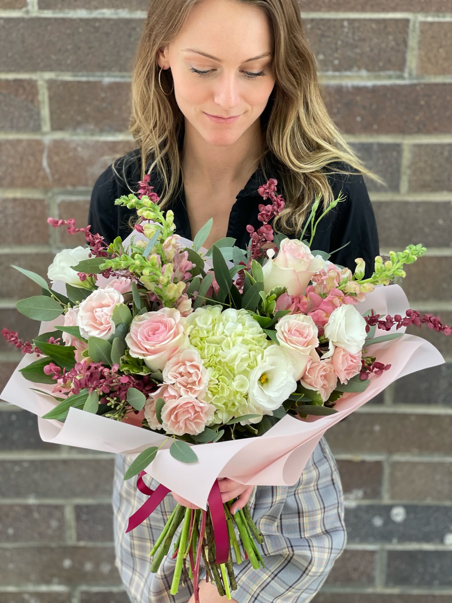 Heart On Your Sleeve Handtied Bouquet - A delicate romantic handtied bouquet with soft white and blush hues and accents of burgundy. This classy bouquet includes mondial roses, tender white lisianthus, elegant snapdragons, garden spray roses, and premium hydrangea. It's the perfect wingman on a third date or a must-have for your wedding anniversary.   Please note that this does not come with a vase.