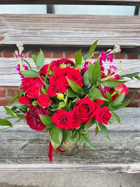 Hopeless Romantic - An all red arrangement using roses, carnations, stock and greenery in a 5x5 cylinder vase. Deluxe and premium arrangements will come in 6x6 vase and include seasonal premium flower.