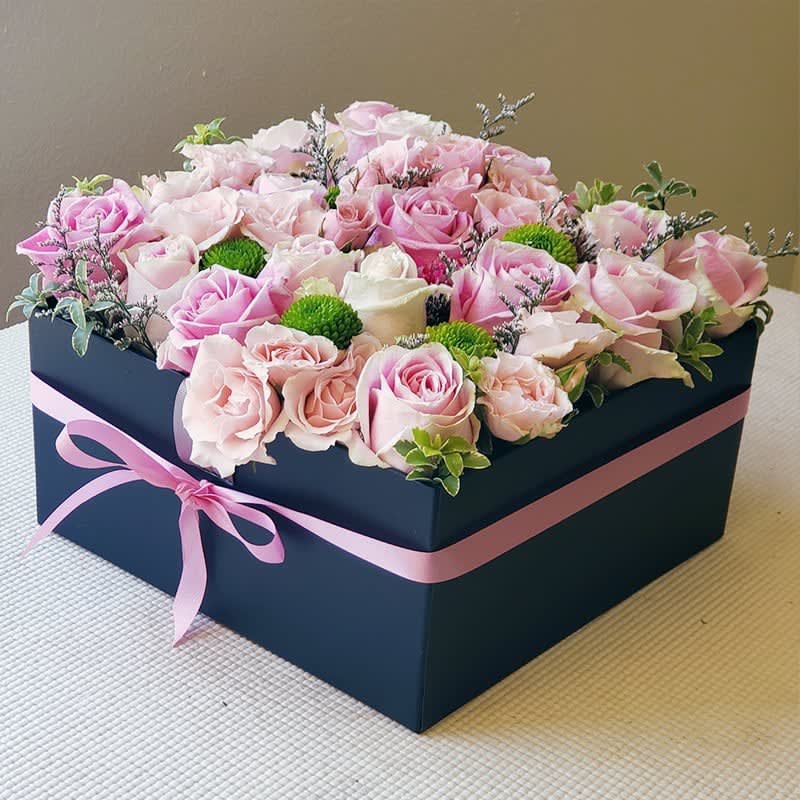 Soft Pink Roses Gift Box - Pink Roses Gift Box with premium fresh-cut pink roses and seasonal accents. This made-to-order bouquet of fresh-cut roses comes in a gift box and is ready to be enjoyed by your loved one.   This boxed bouquet offers a modern twist on a classic gift. It is perfect for anniversaries, or congratulations, or as a stylish centerpiece to add a touch of refined beauty to any setting.   Approximately 7" H x 10" W.   