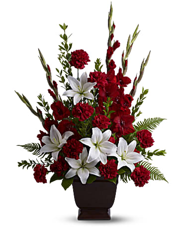Tender Tribute - Heavenly white lilies, rich red carnations and gladioli create a touching funeral arrangement or sympathy bouquet for the service. This red and white sympathy arrangement includes white asiatic lilies, red gladioli, red carnations, myrtle, sword fern and salal. Presented in an exclusive Noble Heritage urn. Orientation: One-Sided
