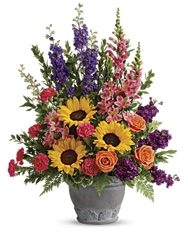 Hues of Hope Bouquet - Send a message of warmth and hope with this magnificent display of sunflowers and roses in a large antiqued pot, a colorful tribute that will warm their hearts.  This bright arrangement includes orange roses, pink alstroemeria, hot pink carnations, yellow sunflowers, purple larkspur, purple stock, hot pink snapdragons, myrtle, variegated pittosporum, and leatherleaf fern. 