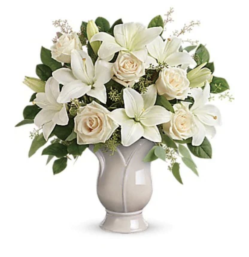 Wondrous Life Bouquet - Celebrate a wondrous life with this timeless tribute of pure white lilies and roses, arranged in a graceful tulip-shaped ceramic vase. This monochromatic bouquet features crème roses, white asiatic lilies, seeded eucalyptus, and lemon leaf. Delivered in a Blooming Tulip vase.