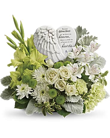 Hearts In Heaven Bouquet - Share your heart and show your love with this magnificent display of green and white blooms, gracefully surrounding an angel's wing keepsake with a loving message of sympathy. Message on sculpt reads: "Because someone we love is in heaven, there is a little bit of heaven in our hearts." White spray roses, white alstroemeria, green gladioli, green carnations, green button spray chrysanthemums, and white cushion spray chrysanthemums are accented with dusty miller, pitta negra, and lemon leaf.