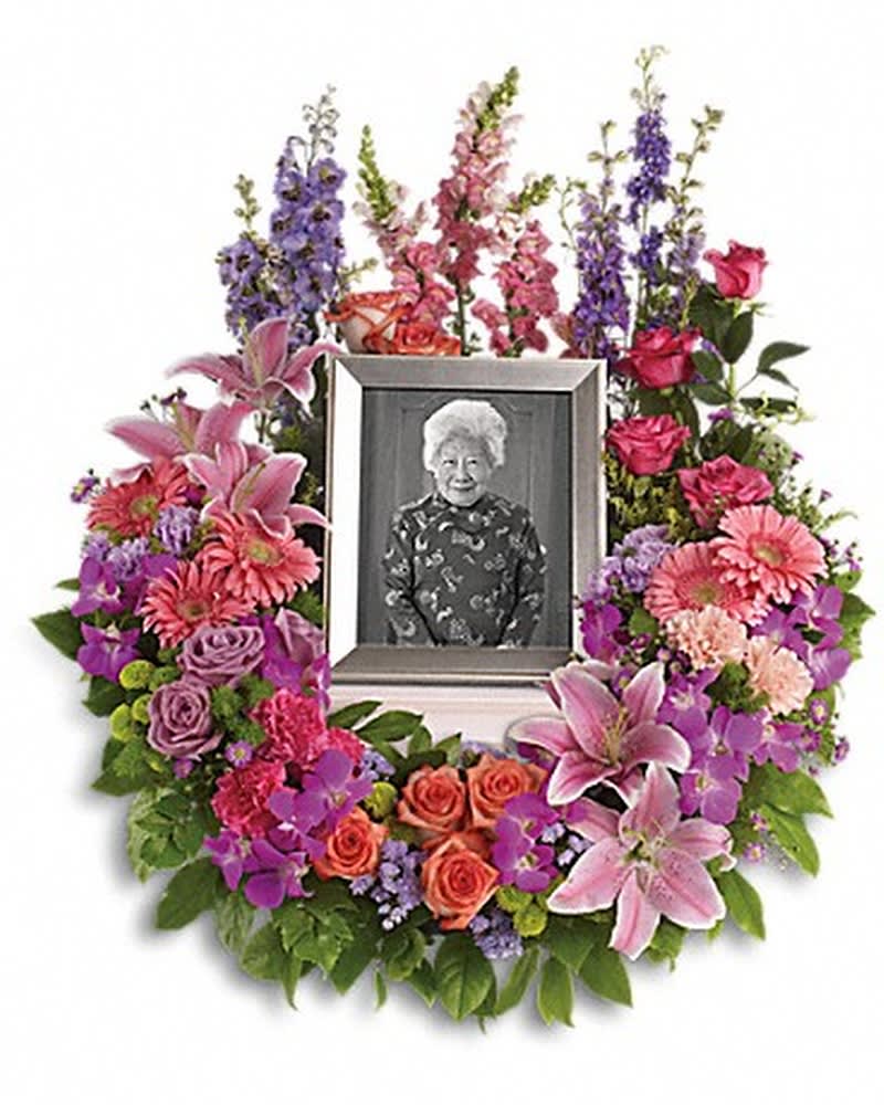 In Memoriam Wreath - Devotion is expressed and beautiful memories cherished with this deep-hued and softly elegant wreath. A lovely reminder of your affection and respect. A mix of dramatic flowers such as purple orchids and asters, orange, dark pink and lavender roses, pink and peach carnations, lavender larkspur, green chrysanthemums, and a range of pink blooms including oriental lilies, gerberas, snapdragons and more. Please note: Arrangement does not include picture frame.