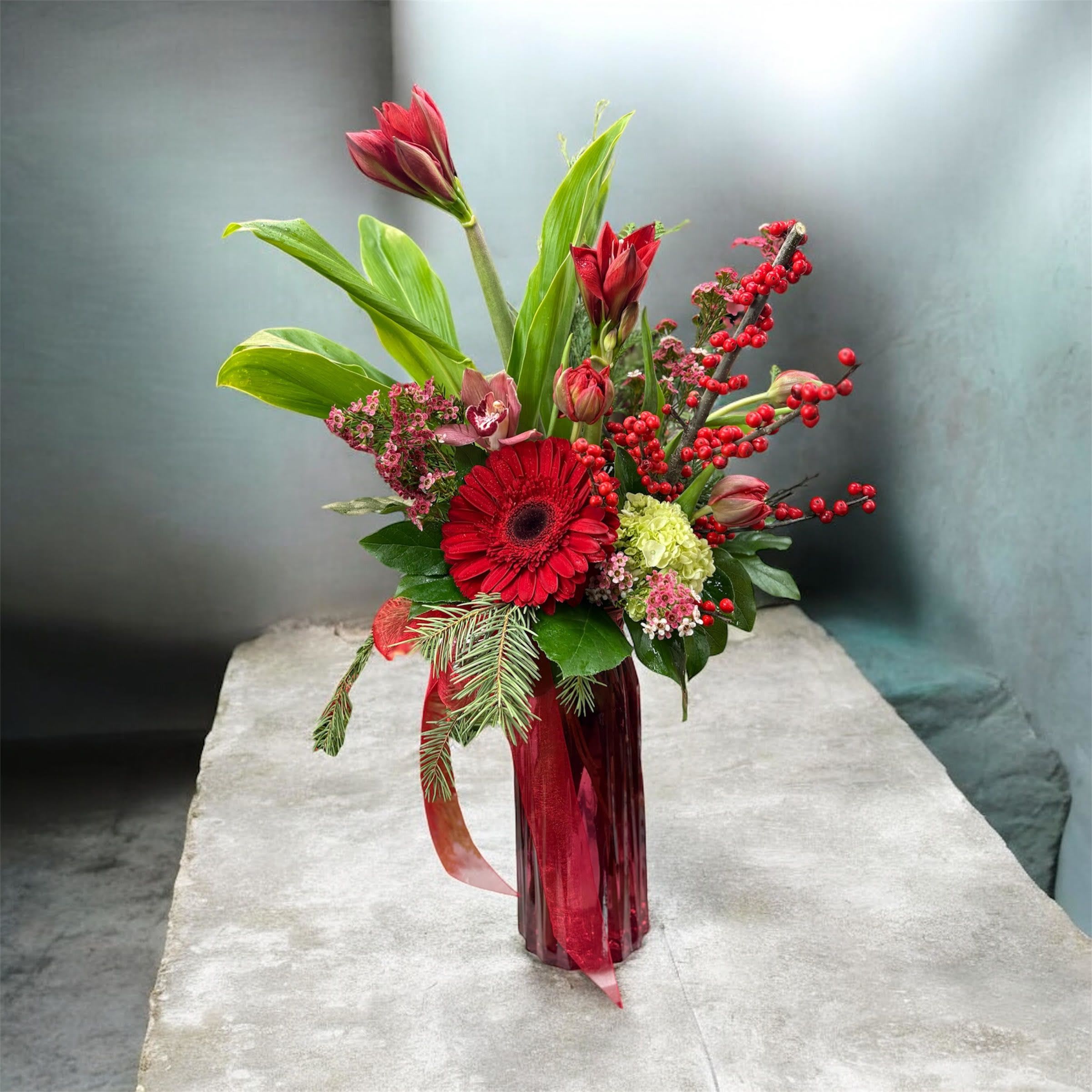 Yuletide Elegance - This Christmas arrangement features a graceful blend of tulips, holly (ilex), and amaryllis, creating a look that is both festive and refined.
