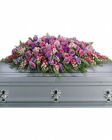 Lavender Tribute Casket Spray - Like a heartfelt embrace, this beautiful casket spray delivers comfort and love in an extraordinary way. A wonderful array of lavender and pink flowers with just the right amount of greenery is a lovely way to pay tribute to someone who will always be with you in heart, mind and spirit. Lovely lavender and pink roses, snapdragons, alstroemeria, chrysanthemums, fern, eucalyptus and more create this tribute that is overflowing with grace and love. Approximately 51" W x 22" H