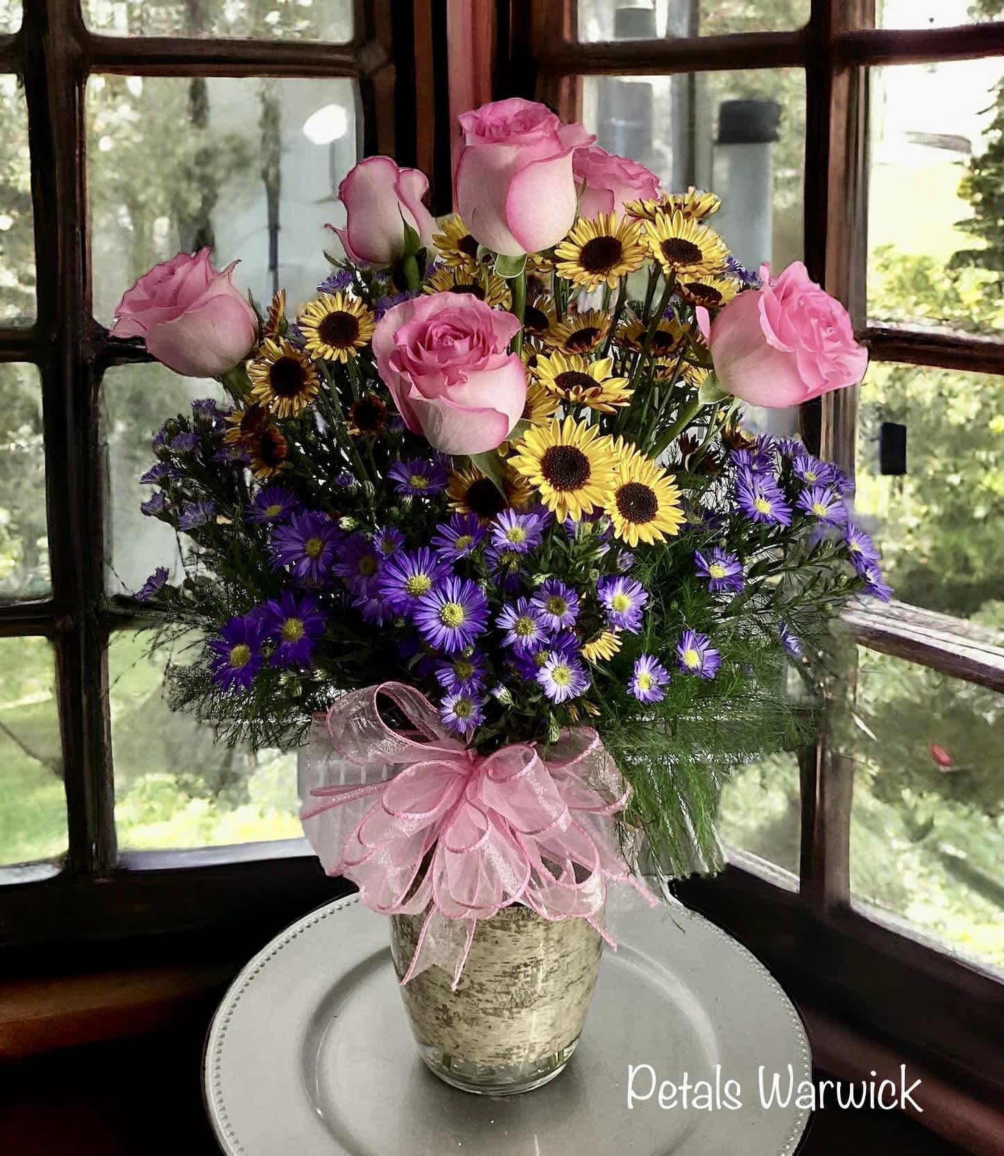 Asters, Daisies and Roses by Petals    - This combination of flowers speaks volumes, making it perfect for Mother's Day, birthdays, anniversaries, expressions of friendship, or simply "just because." Purple asters symbolize love, patience, wisdom, elegance, and grace, making them an ideal gift for a loved one. Yellow daisy poms represent joy, optimism, friendship, cheerfulness, and positivity. Pink roses typically symbolize love, gratitude, and appreciation.