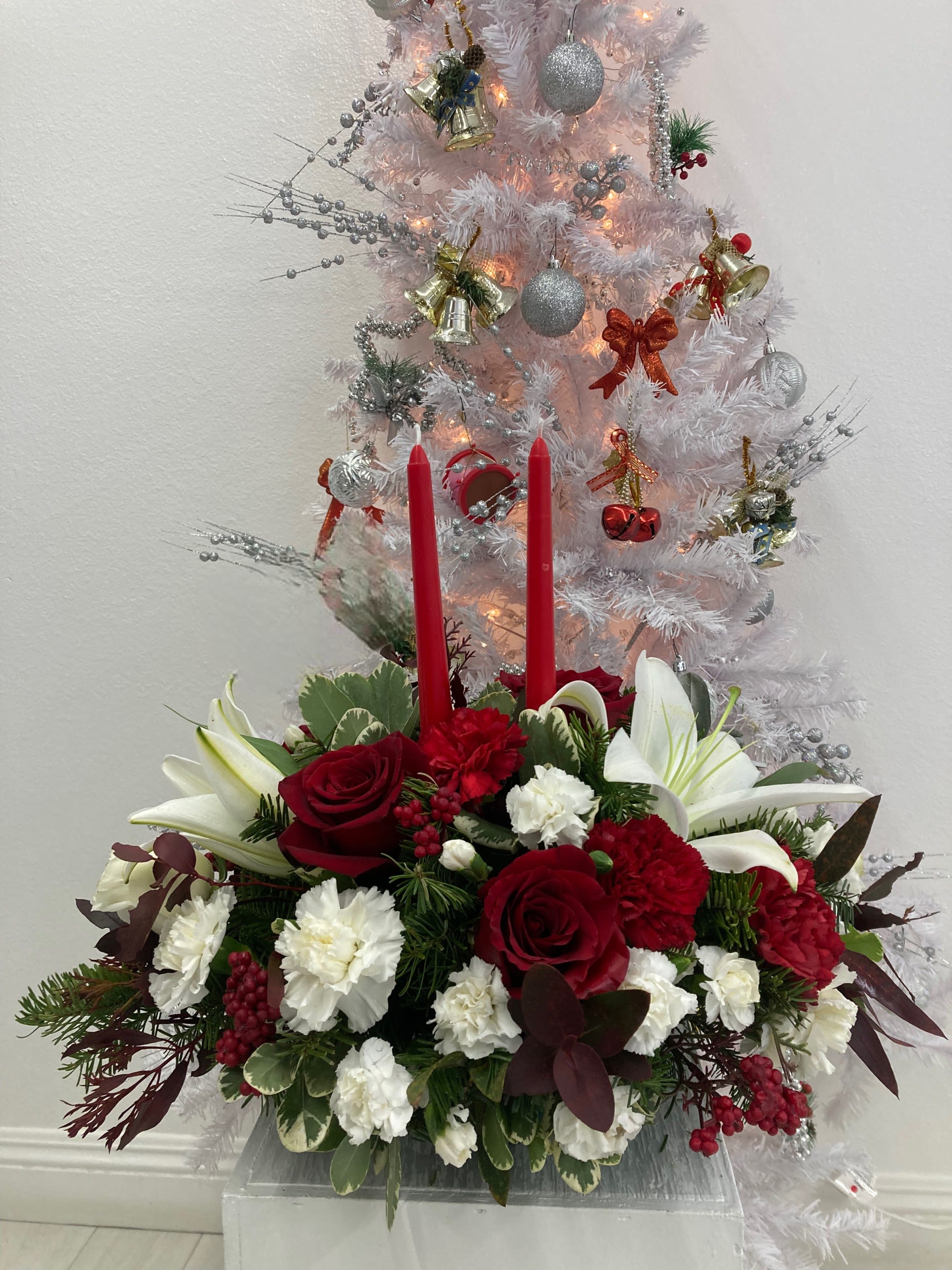 Crimson Candle Glow - Celebrate the season with Crimson Candle Glow, a classic Christmas centerpiece designed to bring warmth and elegance to any holiday table. Lush foliage and seasonal greenery complete the look, creating a timeless centerpiece perfect for Christmas dinners, festive gatherings, or gifting. (If some flowers and/or the vase are not available there will be minor substitutions.)