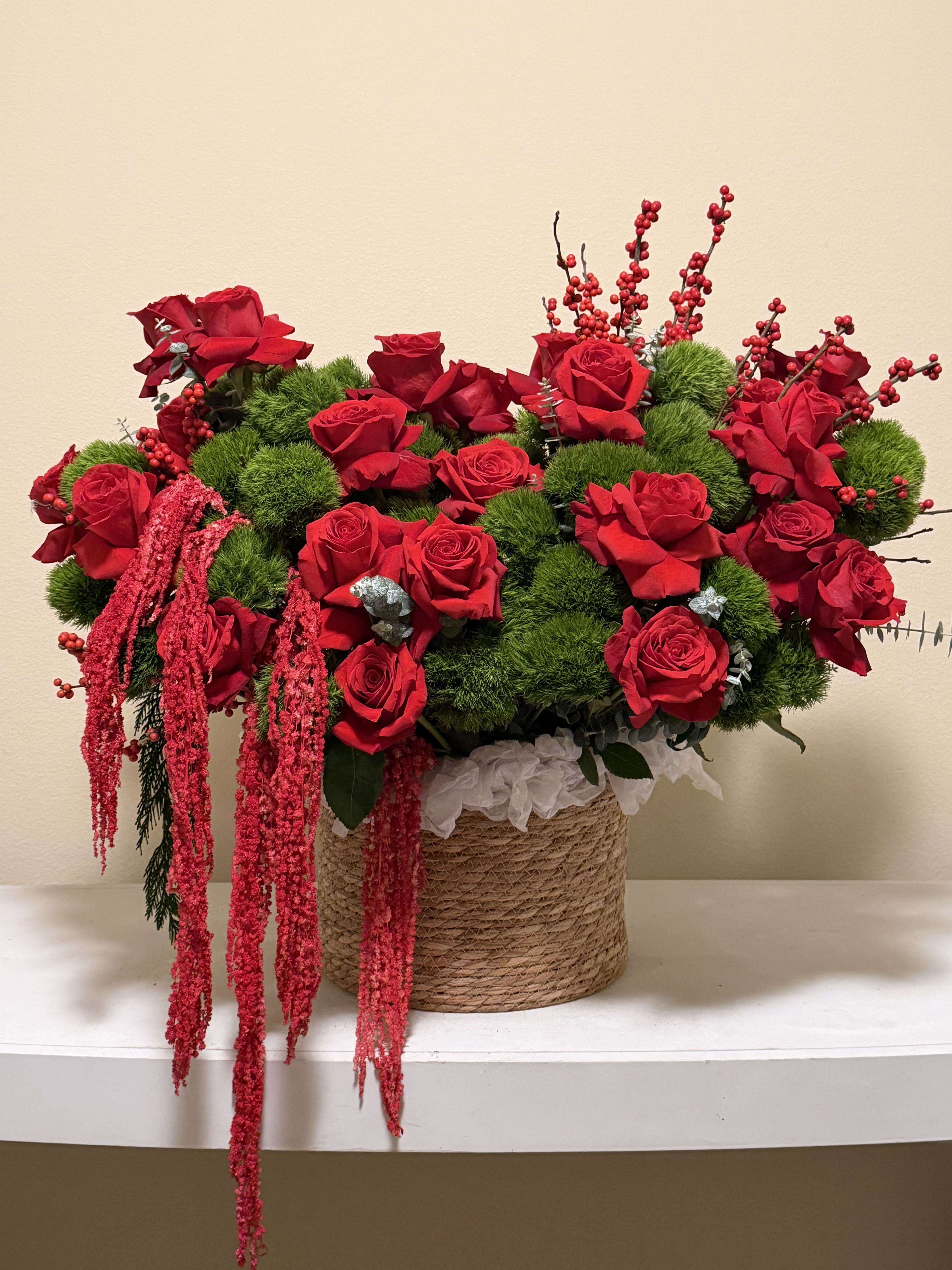 Enchanted Red Basket - Elevate any space with the striking elegance of this luxurious floral arrangement. Lush, velvety red roses take center stage, beautifully complemented by textured greenery and cascading accents that create movement, depth, and sophistication. Designed in a stylish rope-wrapped base, this arrangement blends natural charm with refined artistry, making it perfect for special celebrations, romantic gestures, seasonal décor, or premium gifting. Rich, vibrant, and full of presence, it’s a breathtaking statement piece that captures passion, warmth, and timeless beauty.