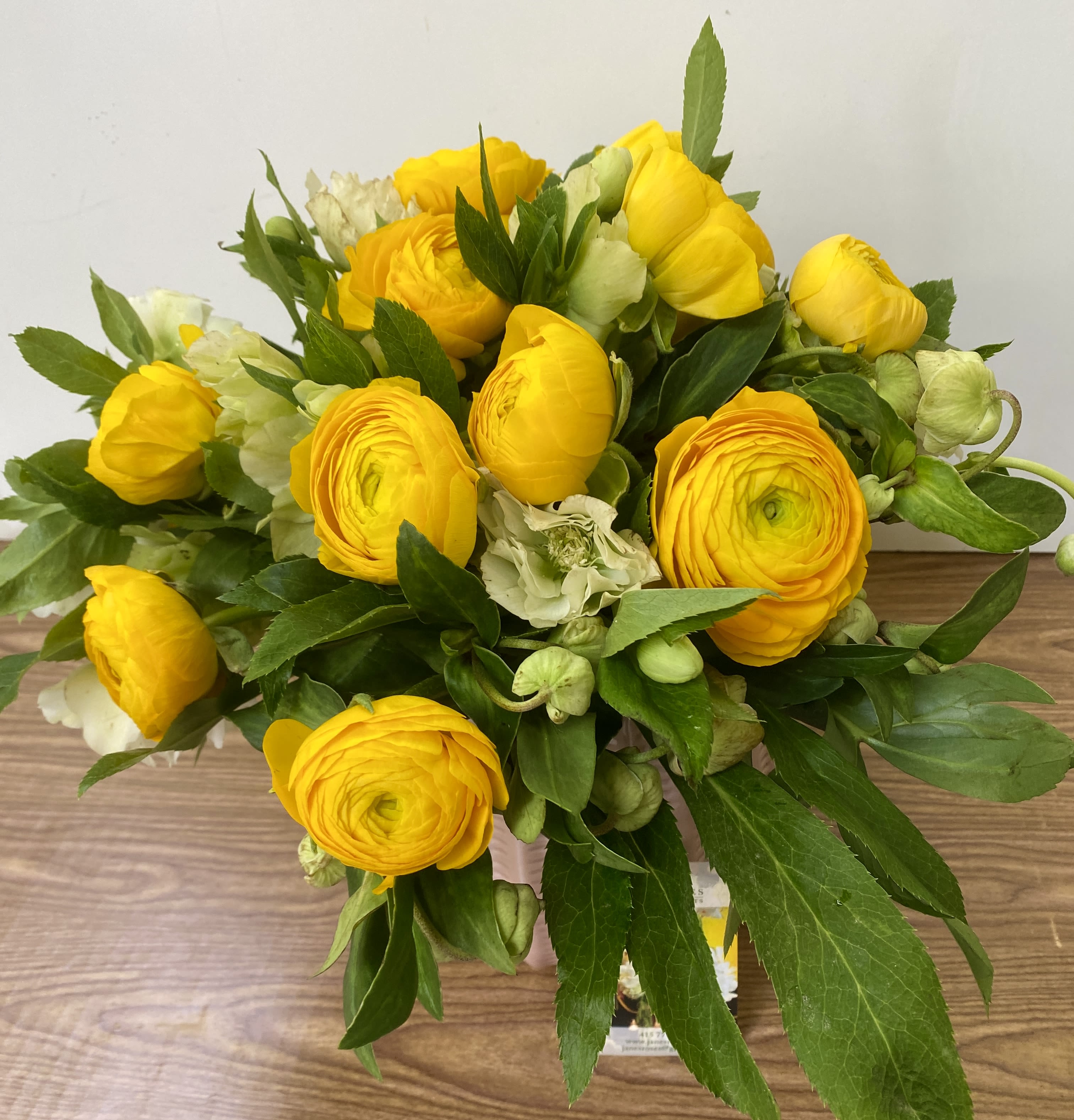 FLY ME TO THE MOON - COMBINATIONS OF YELLOW RANUNCULUS and HELLEBORES IN A BEAUTIFUL CERAMIC VASE