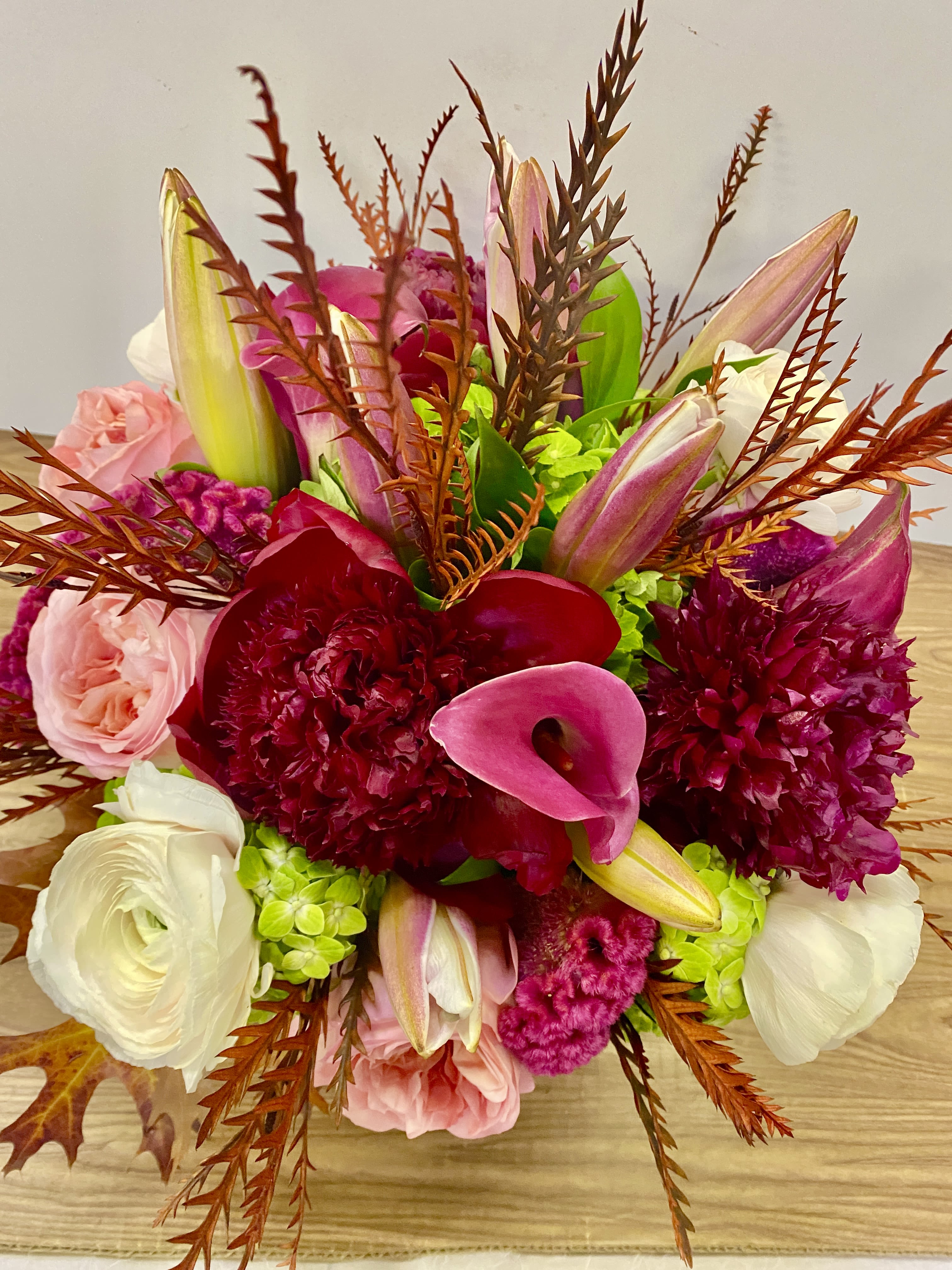 METRO IN DINO - In a glass vasr combinations of pink roses white ranunculus and no colors are red, peonies, and lilies and green hydrangeas