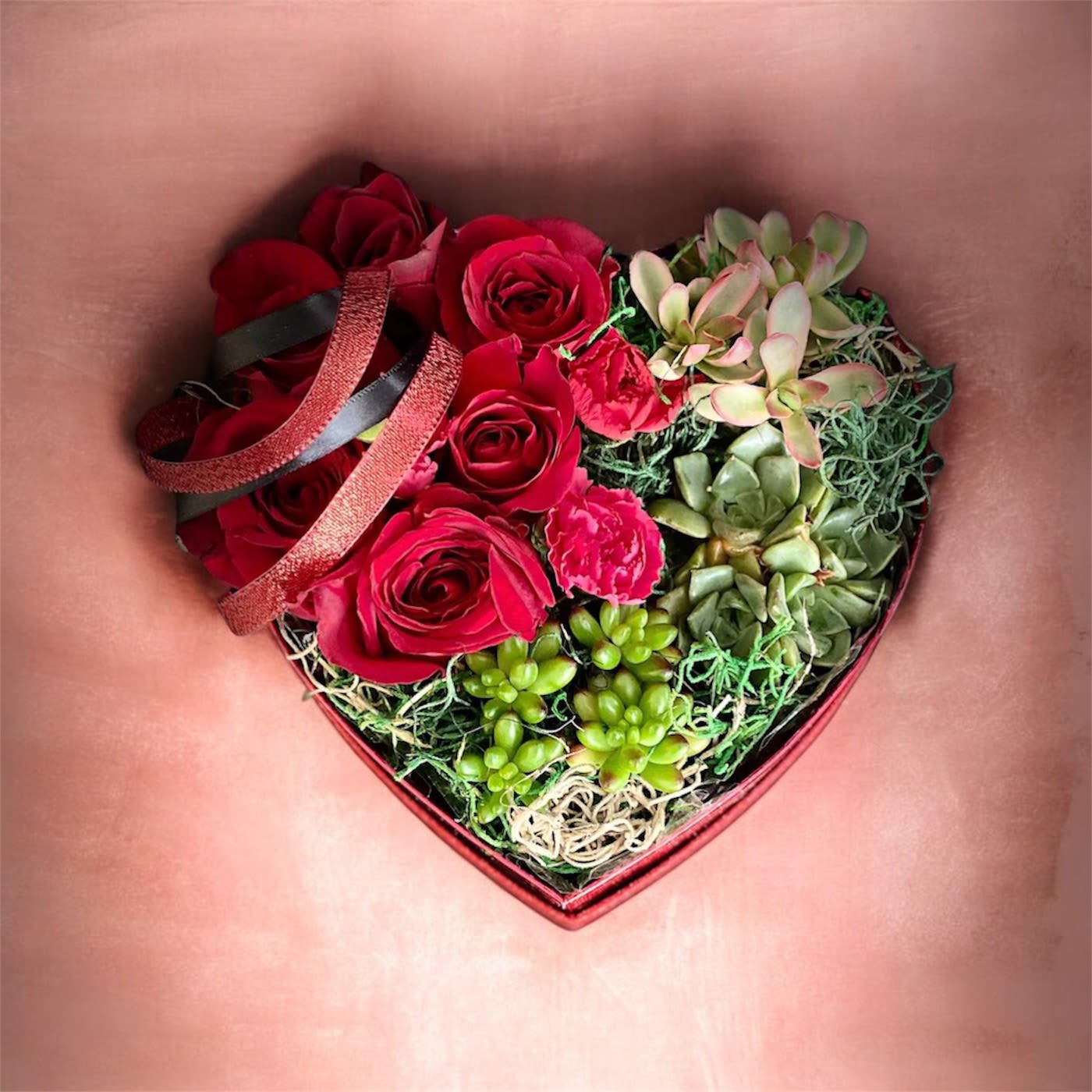 Roses And Succulents - Elevate romance with our Heart-Shaped Box featuring a perfect union of velvety roses and resilient succulents. This exquisite arrangement symbolizes enduring love, blending the classic allure of roses with the modern charm of succulents – a distinctive and everlasting expression of affection beautifully nestled in a heart-shaped box." *Flower colors may vary depending on availability 