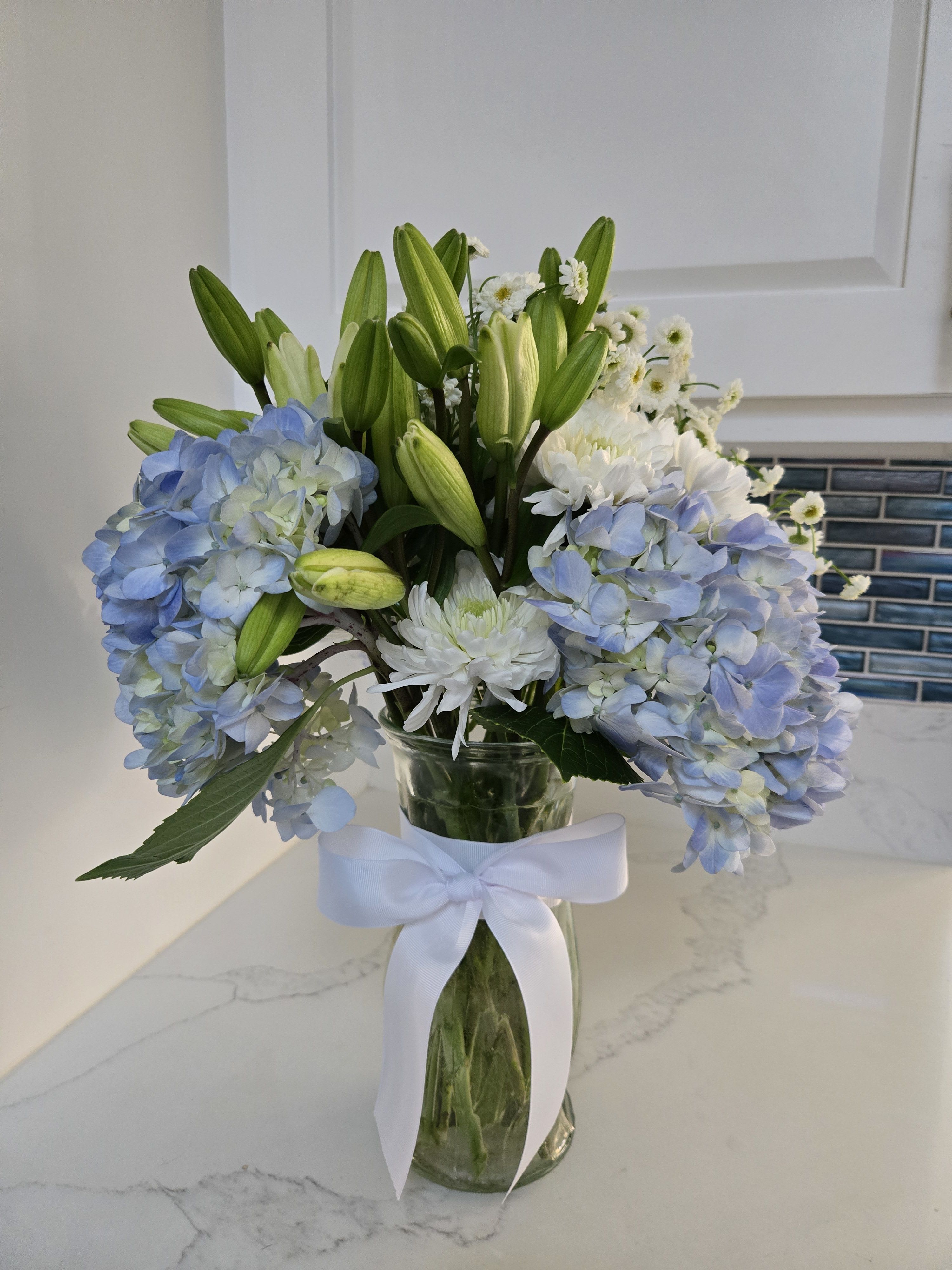 Tranquility - Contains 20 stems of white and blue blooms.  Displayed in a clear glass vase.