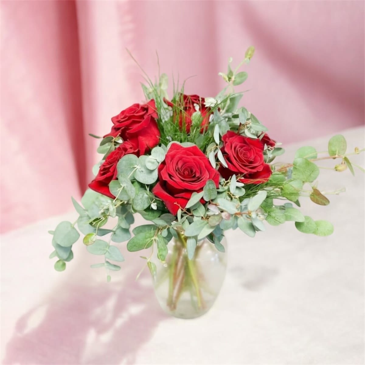 Simply Romantic - Let your love speak for itself with our Simply Romantic arrangement. This timeless design features lush red roses accented with soft eucalyptus and airy greenery, arranged in a clear glass vase. Elegant and understated, it’s the perfect gesture for anniversaries, just because, or any heartfelt moment.  Vase style and greenery may vary based on availability. 