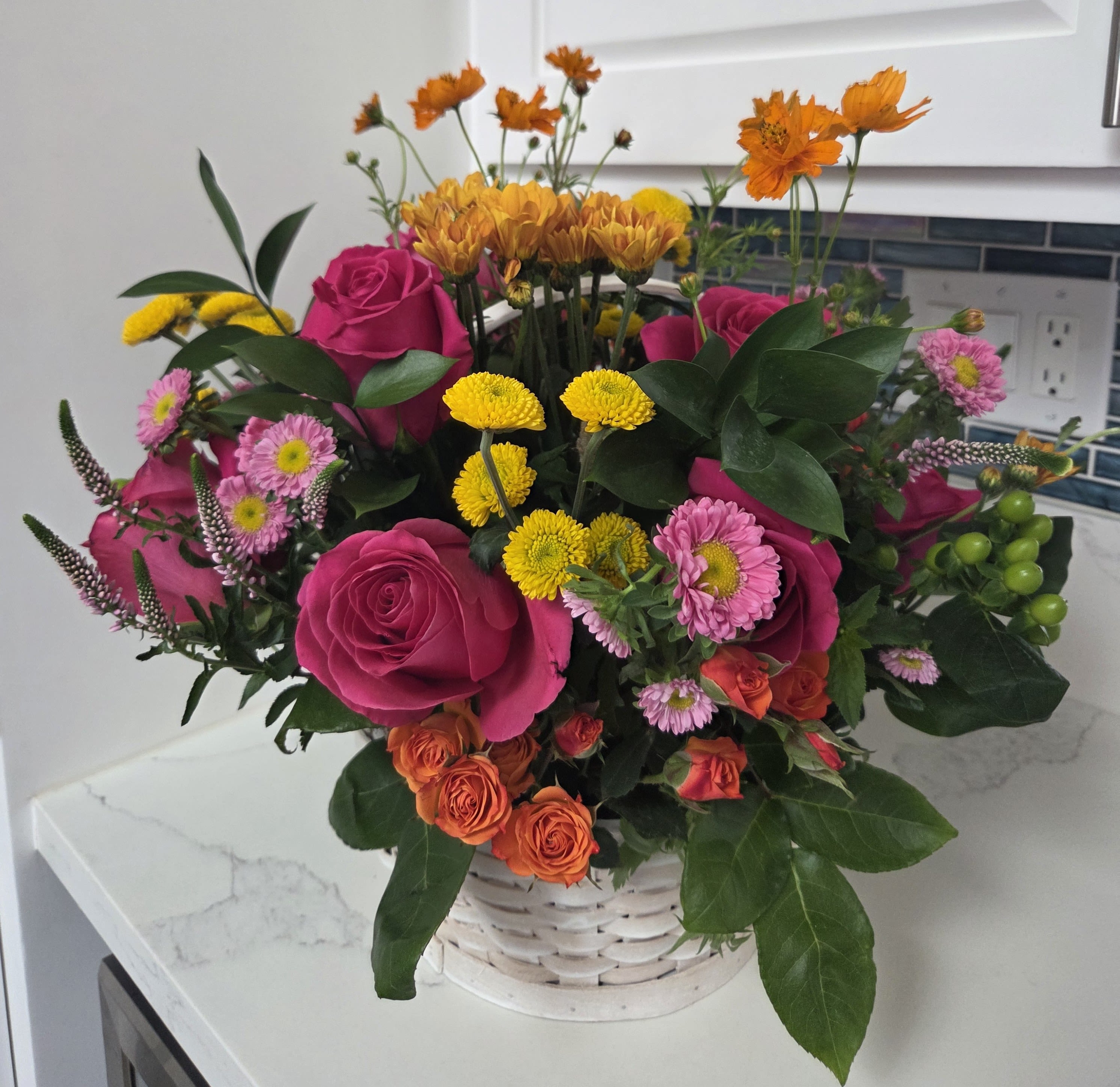 Spring Flower Basket - A basket of bright goodness to bring joy to whoever receives it. This basket will look like it was fresh picked from a field, containing hues of pink, yellow, orange and green blooms .