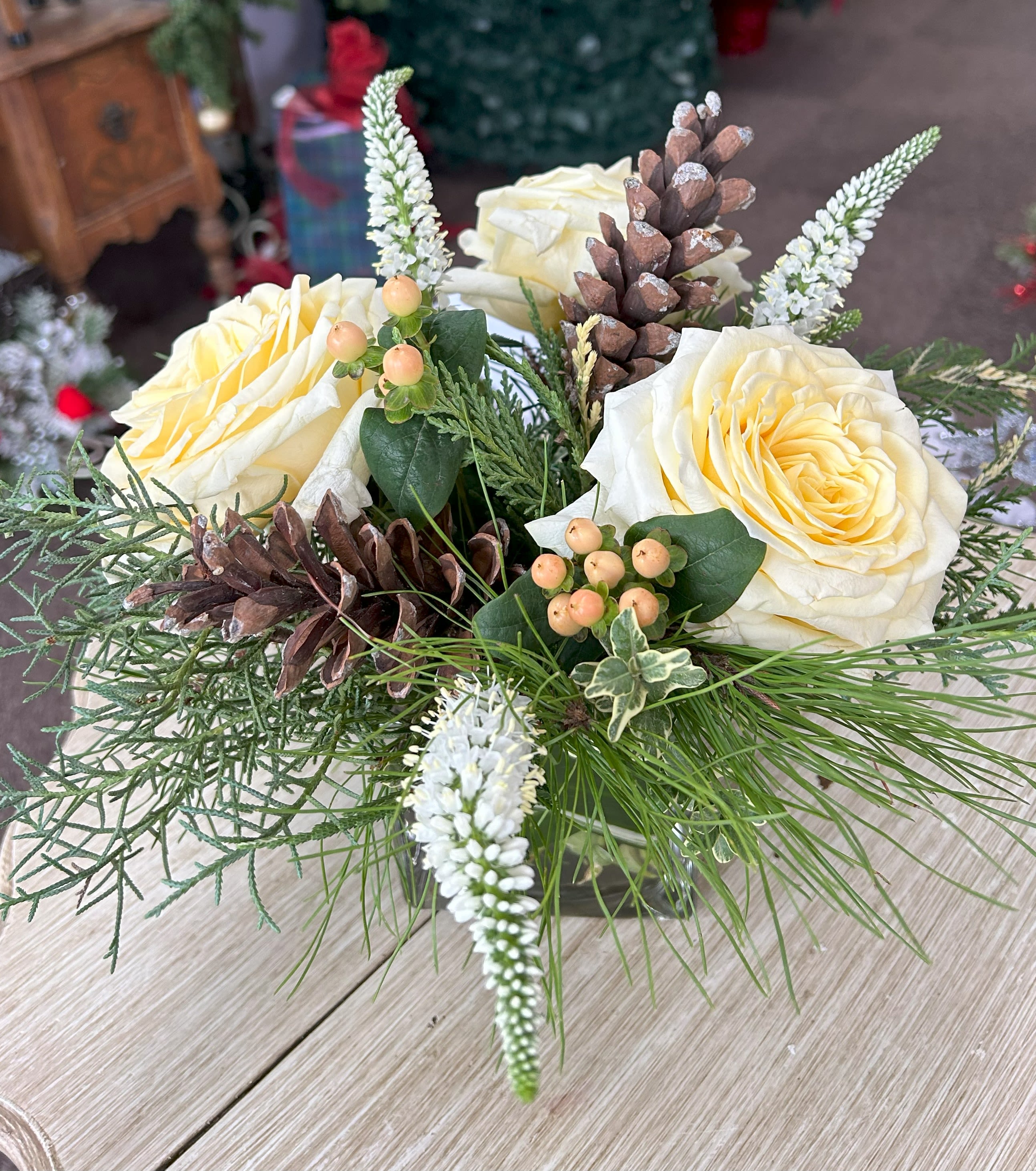 White Christmas Roses - 4" Cube with Christmas greens, white roses, veronica, hypericum berries, and pinecones. 