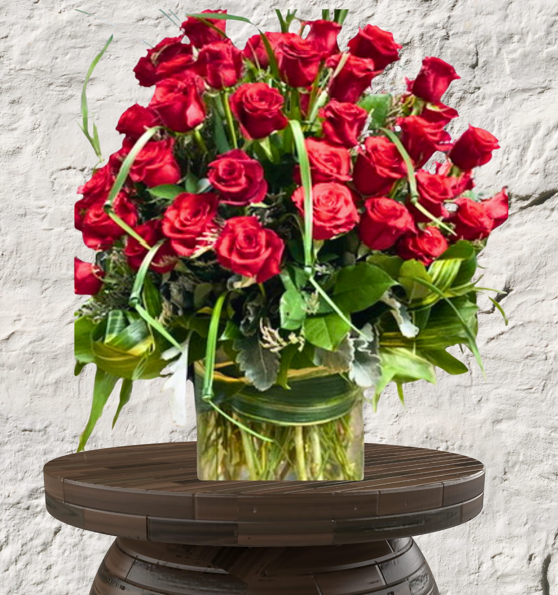 The Scarlet Sovereign -   The Scarlet Sovereign: Rose Collection Unapologetic Opulence. Timeless Romance. Architectural Grandeur.  The Scarlet Sovereign is the ultimate expression of luxury, designed for those who want to make an unforgettable statement. This high-density arrangement is a masterclass in monochromatic drama, featuring premium, long-stemmed red roses that signify a love—or a style—without limits.  The Design &amp; Florals This "Sovereign Statement" piece is engineered for maximum visual impact and architectural height.  Premium Blooms: An overflowing abundance of designer-grade red roses, selected for their high petal count and rich, velvet-like texture.  Lush Foundations: The roses are supported by a deep architectural base of variegated tropical greens and silver-toned foliage.  The Upscale Vessel: Presented in a heavy-weighted, oversized glass cylinder with stems artfully concealed by a hand-wrapped tropical leaf lining for a sophisticated finish.  Select Your Level of Grandeur We offer this masterpiece in two tiered counts to suit the scale of your celebration:  The Sovereign 50: A breathtaking display of 50 premium roses, perfectly balanced for a luxury dining table or grand entryway.  The Sovereign 100: Our most opulent offering. A towering, massive arrangement of 100 roses designed to serve as a high-end event focal point or the ultimate romantic gesture.