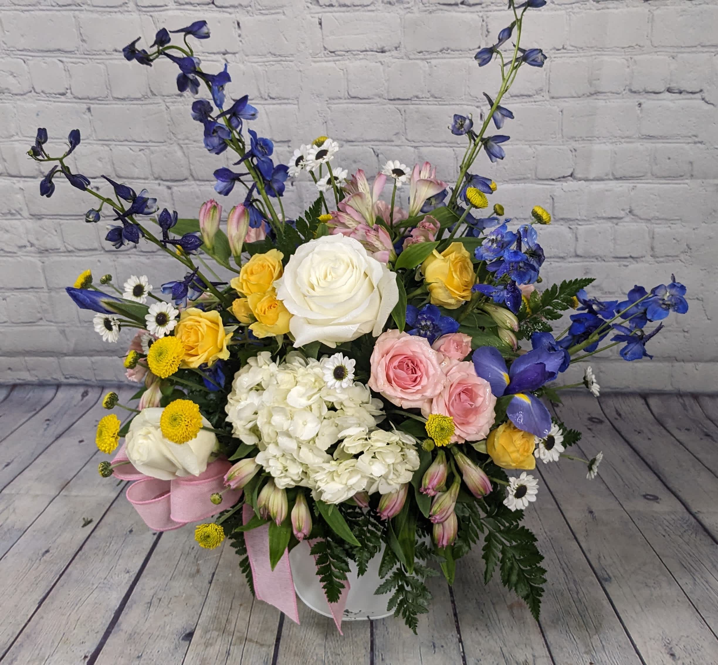 Garden Gathering - This large bouquet features striking iris, hydrangea, delphinium, pure white roses, adorable ying-yang daisies, and mixed-color spray roses. It's as if you wandered through a lush flower garden and gathered the very best of spring's blooms. 
