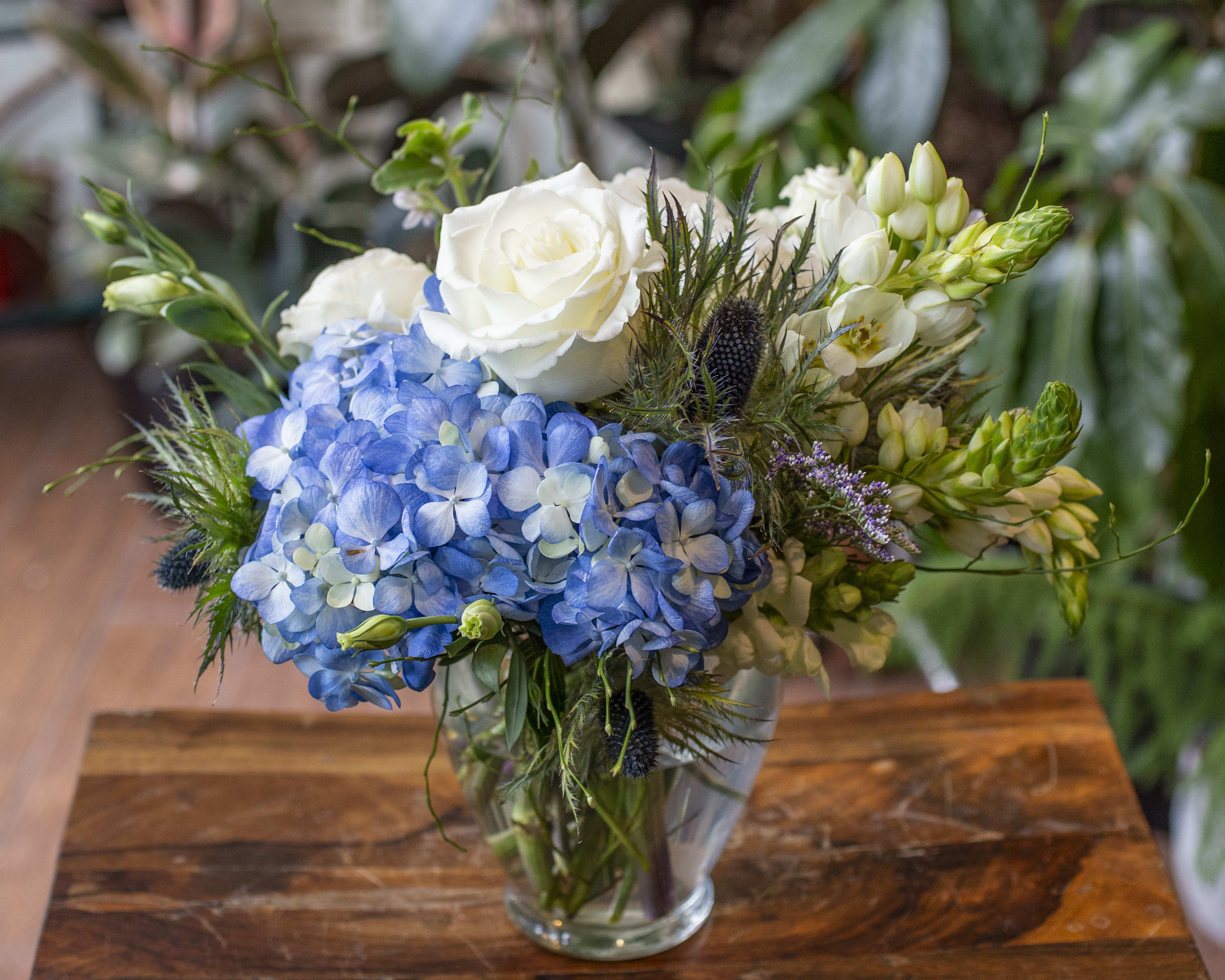 Diego - Exciting bunch of blue, white and green flowers in a clear glass vase.