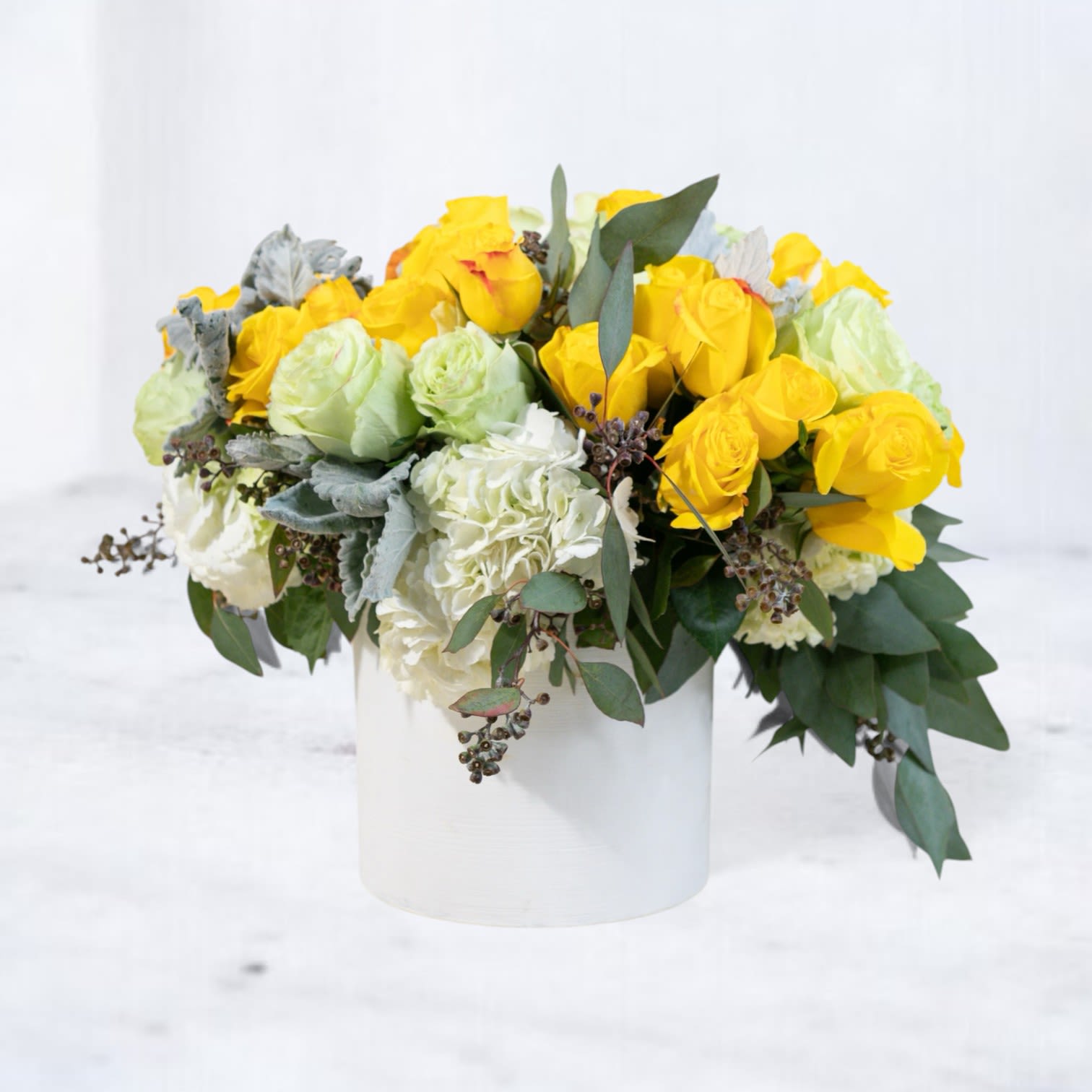 Sunlit Luxe Arrangement - Illuminate any occasion with the Sunlit Luxe Arrangement, a radiant composition of golden yellow roses, creamy white hydrangeas, and soft green blooms. Accented with lush eucalyptus, this bouquet is a luxurious celebration of light and elegance. Perfect for birthdays, anniversaries, or simply to brighten someone’s day, this design is presented in a modern white vase, adding a chic touch to its timeless beauty.