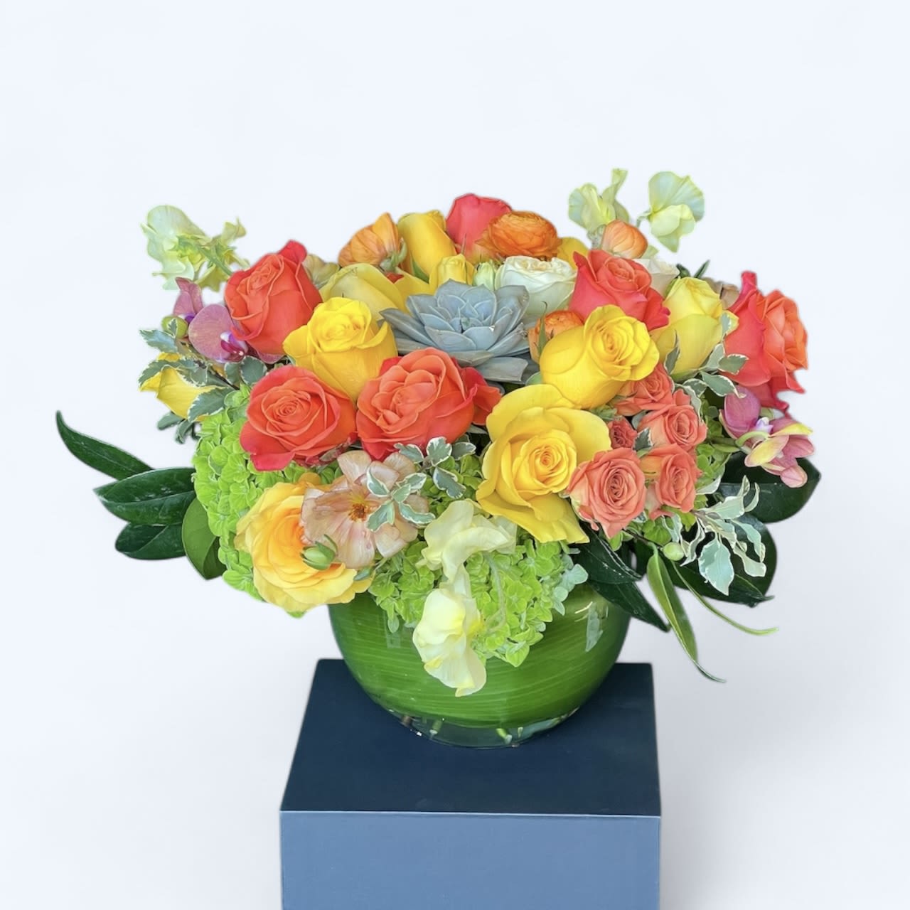 Folkloric  - This cheery vase arrangement is bursting with bright orange and yellow Roses, with Hydrangea, greenery, and topped with a Succulent