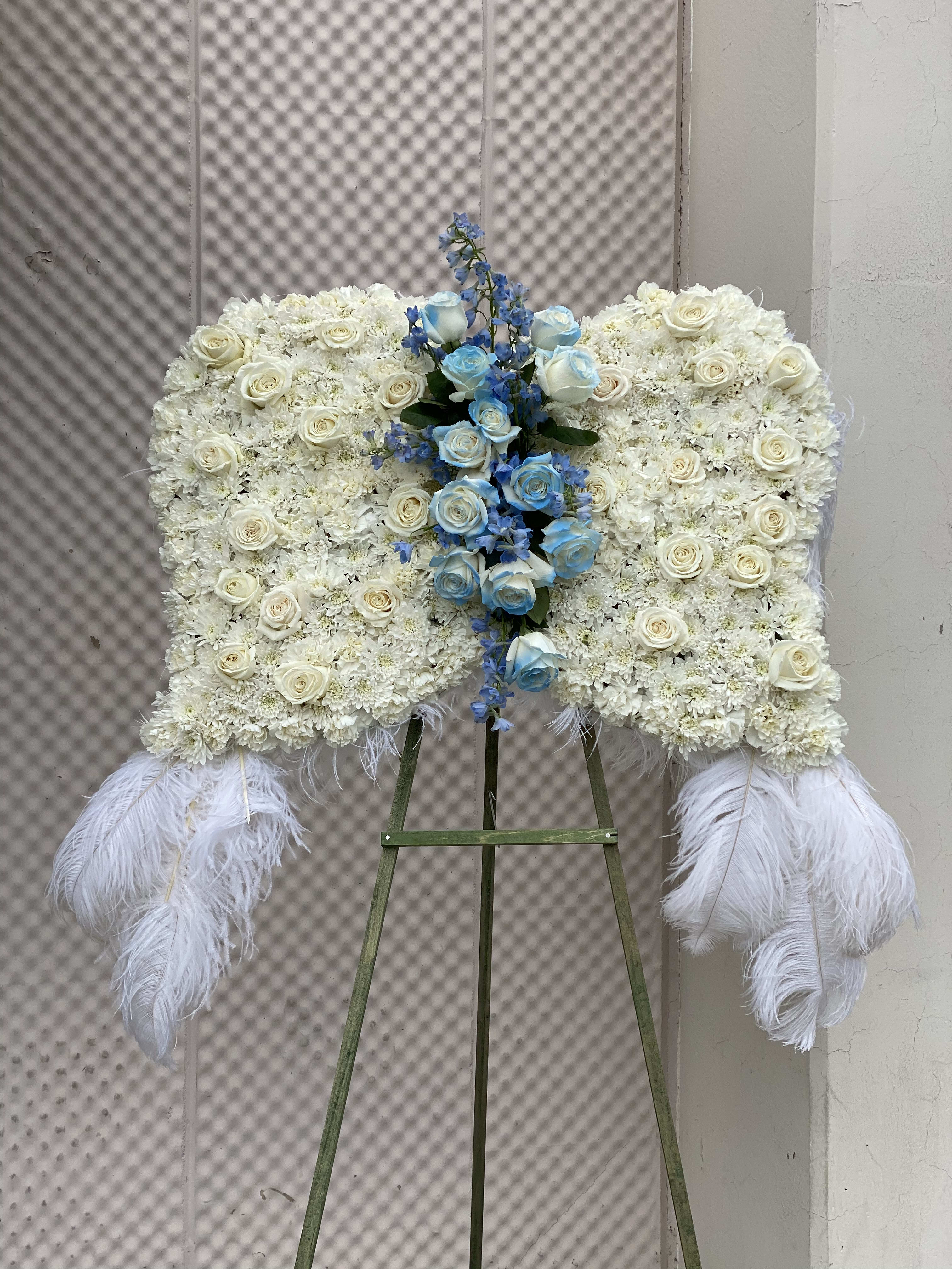 Angel Wings Blues - Angel wings with blue cluster in center this beautiful design is made with roses, carnations, chrysanthemums, And blue delphinium