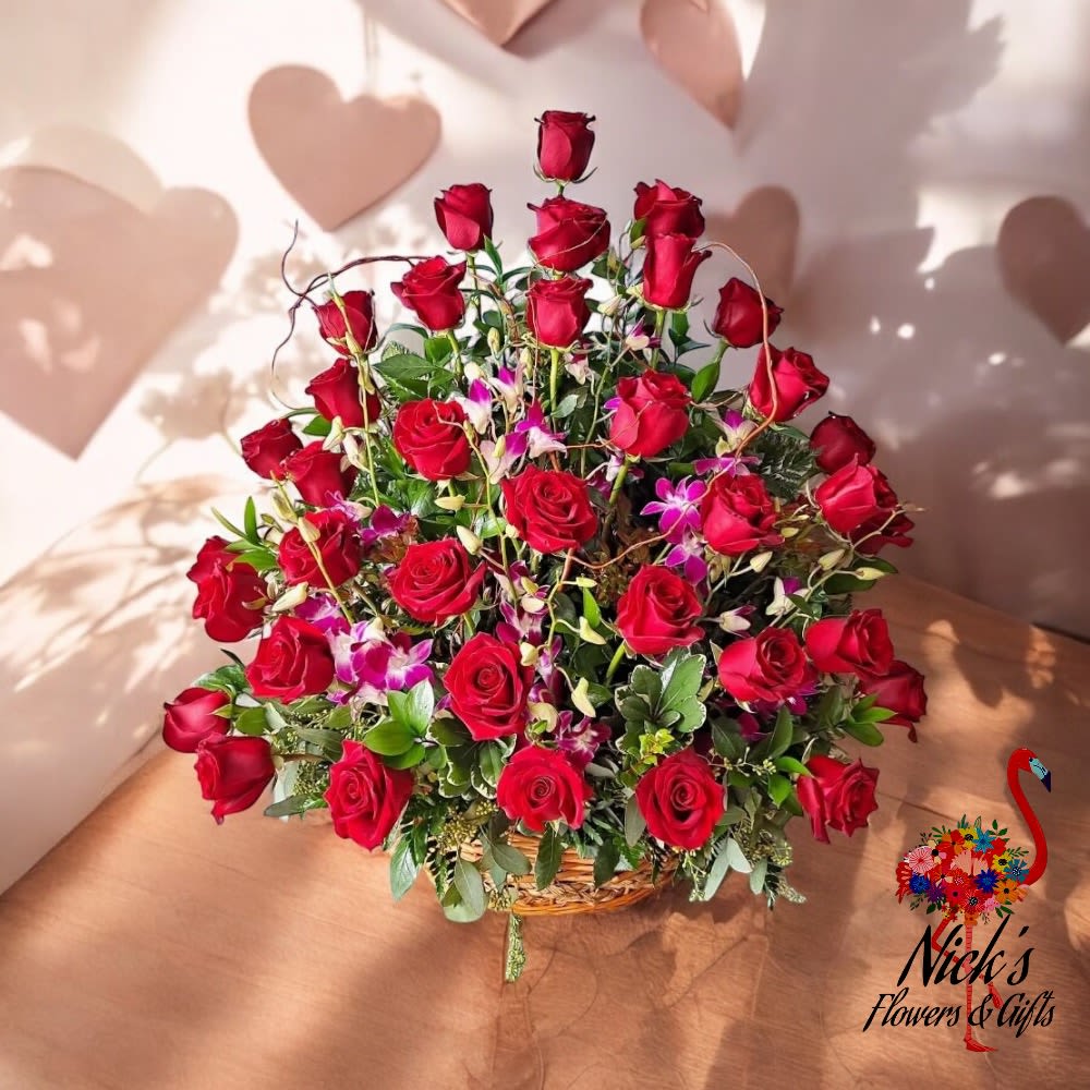 Loves Enchantment Basket - * The "Love's Enchantment Basket" is a captivating arrangement that beautifully captures the essence of Valentine's Day. This exquisite basket features an enchanting blend of velvety red roses and delicate orchids, symbolizing deep love and admiration. The lush greens provide a vibrant backdrop, enhancing the rich colors and adding a touch of natural elegance.  The arrangement is thoughtfully designed to create a harmonious balance, with the boldness of the red roses complementing the graceful allure of the orchids. The lush greenery weaves through the flowers, adding texture and depth to the display.  Perfect for expressing heartfelt emotions, the "Love's Enchantment Basket" is an ideal gift for Valentine's Day, leaving a lasting impression of romance and sophistication. Whether for a beloved partner or a cherished friend, this arrangement is sure to convey your deepest sentiments with beauty and grace.