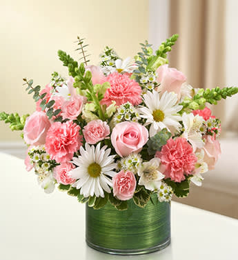 Bubble gum retreat - Product ID: 95391   Make an elegant gesture of condolences with a beautiful, hand-crafted arrangement of pink roses and carnations, gathered with white snapdragons, alstroemeria and daisy poms. A memorable way to remember loved ones during times of sorrow. Graceful arrangement of pink roses, white snapdragons, white alstroemeria, pink carnations, white daisy poms, white mini carnations and white monte casino, gathered with variegated pittosporum and spiral eucalyptus Hand-designed by our expert florists in a stylish clear glass cylinder vase wrapped with a Ti leaf ribbon; vase measures 6"H Appropriate for the service or the home of friends and family members Large arrangement measures approximately 16"H x 17"L Medium arrangement measures approximately 15"H x 16"L Small arrangement measures approximately 14"H X 15"L Our florists hand-design each arrangement, so colors, varieties, and vase may vary due to local availability
