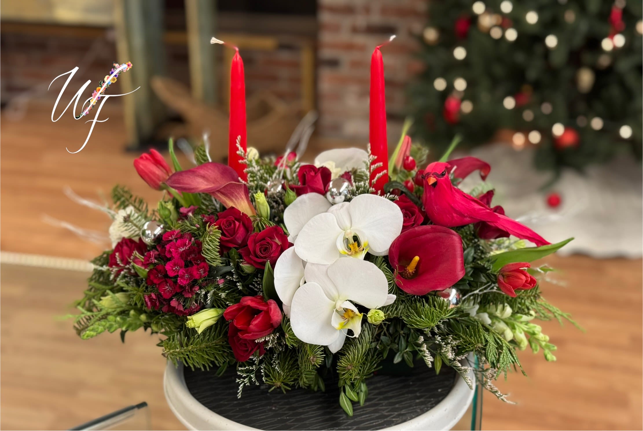 Cardinals Christmas Table  - Beautiful display of cardinals nestled in evergreens and red and white florals. Long and low centerpiece with tapered candles. 