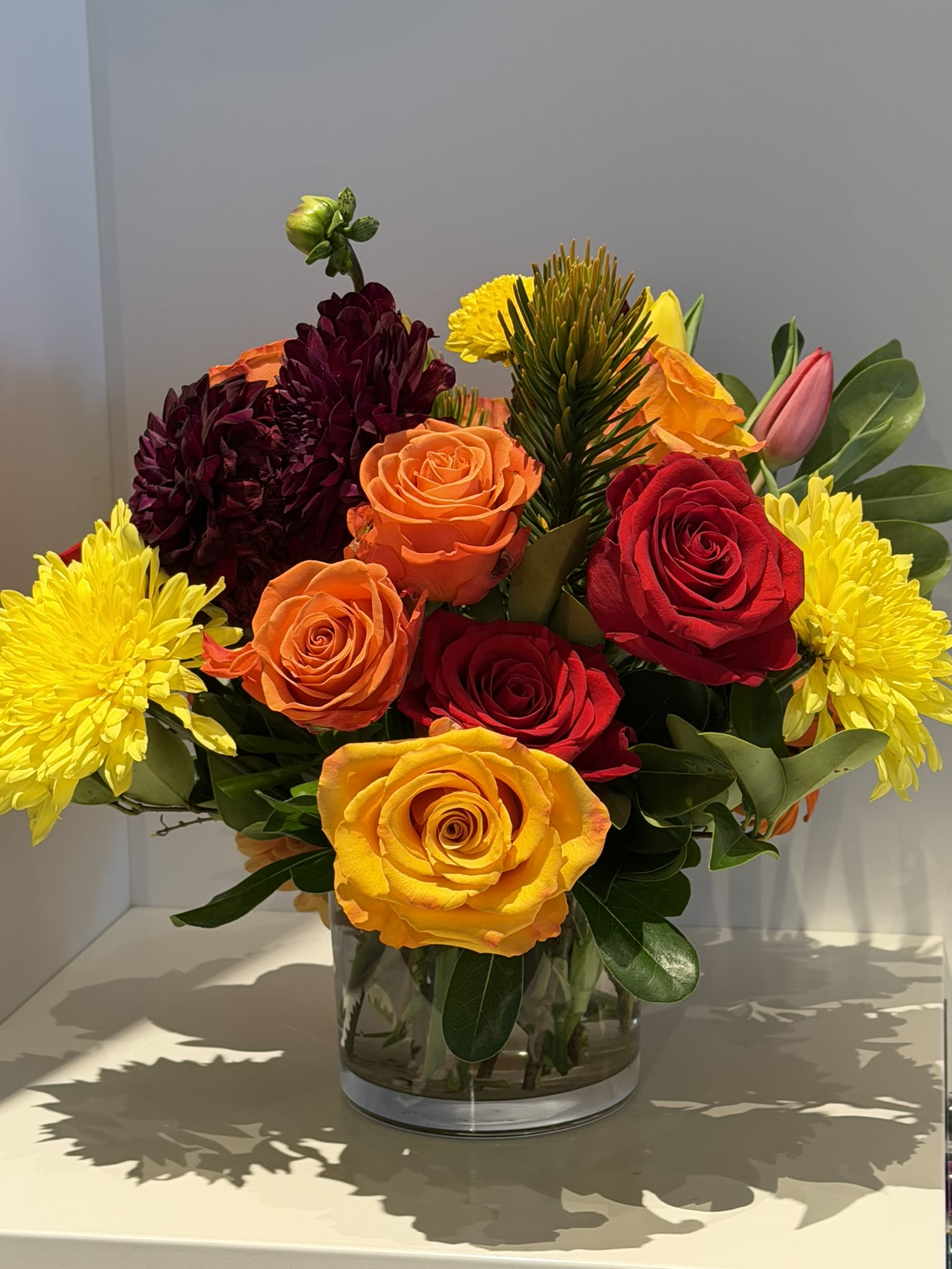 Autumn Splendor - Enjoy all the jewel tones of autumn - the rich burgundies, reds, oranges, golds, and yellows - all in one spectacular arrangement. Including roses, dahlias, tulips, chrysanthemums, and other fall surprises, this long-lasting design will brighten and warm up every space. 