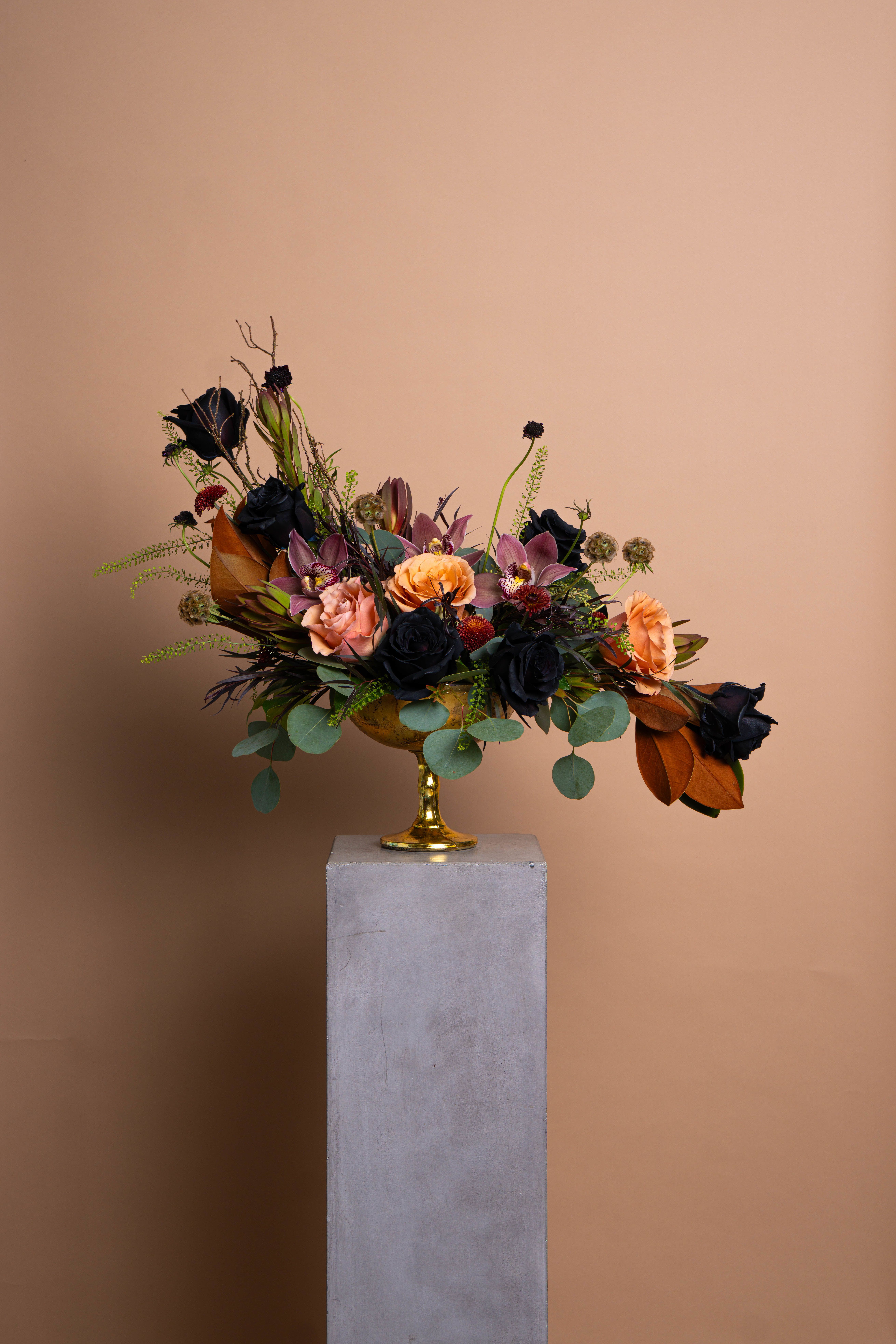 PENELOPE - Composed in shadow and light. Penelope is a study in tension, black garden roses against muted peach and orchid tones, grounded by magnolia and eucalyptus. Each stem placed with intent, every curve deliberate.  Elegant, restrained, and quietly sensual, Penelope evokes the stillness of modern luxury.  The arrangement pictured is Deluxe. May be curated smaller at the Standard price, or elevated with the Premium option.