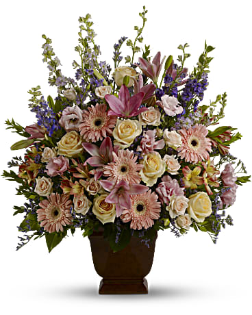Loving Grace - Honor a beautiful person with a beautiful bouquet. This lush, luxurious arrangement of assorted funeral flowers communicates your sympathy in soothing shades of soft pink, peach and lavender. This dramatic display of blooms features flowers such as peach roses, light pink spray roses, pink asiatic lilies, pink gerberas, pink alstroemeria, pink lisianthus, lavender and purple larkspur, purple limonium and greens including myrtle and salal. Delivered in an exclusive Noble Heritage urn. Orientation: One-Sided