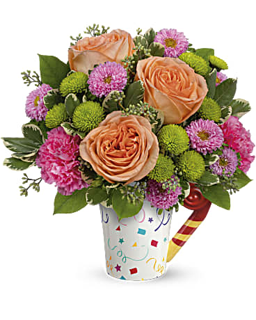 Time To Celebrate by BloomNation™ - Bursting with birthday cheer! This colorful, confetti-covered ceramic mug brightens their special day with beautiful blooms, then cheers them up as a food-safe mug for sipping yummy drinks all year long! This fun bouquet features peach roses, pink matsumoto asters, green button spray chrysanthemums, dark pink carnations, variegated pittosporum, lemon leaf and seeded eucalyptus. Delivered in Teleflora's Cheers to You mug. APPROXIMATE DIMENSIONS: 12"H x 11 1/2"D