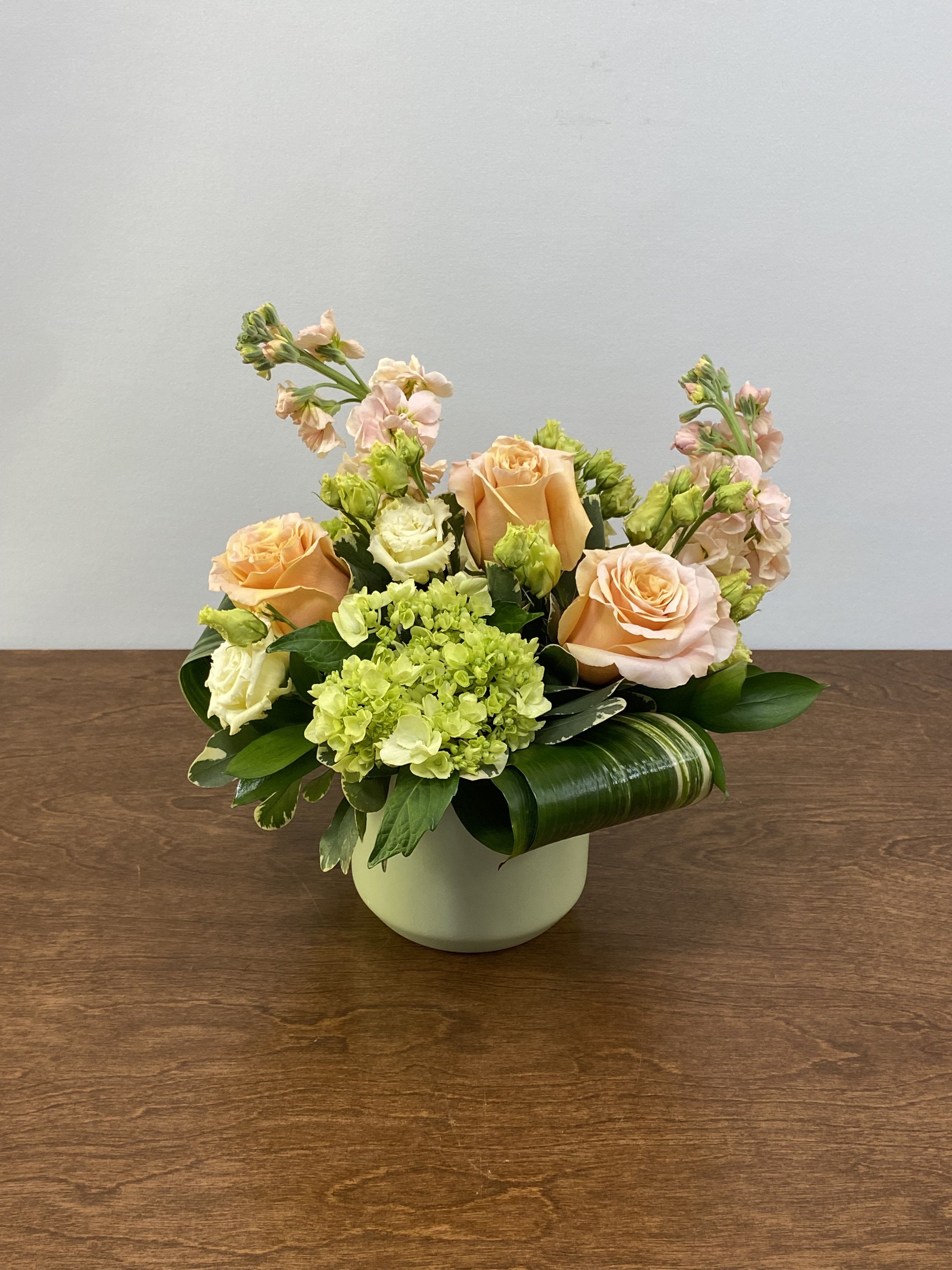 Peach Mojito - This fresh and fruity arrangement is perfectly arranged in time for the Summer season! Peachy Shimmer roses combine with mini green hydrangea, peach stock flower, and cream lisianthus to create a design that will surely match anyone's tastes!