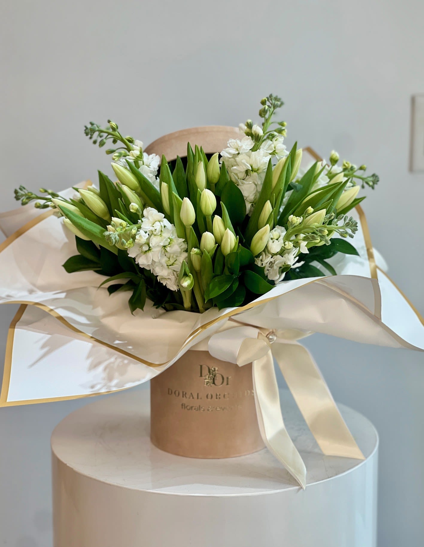 Tulips in a box - white - A clean, elegant mix of white tulips, stock, and fresh greenery arranged in our signature velvet hat box. Soft, timeless, and luxurious—perfect for any occasion that calls for purity and sophistication.