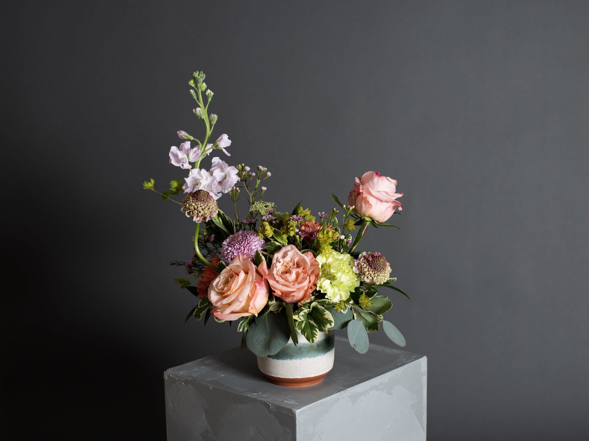 Petra, Wanderlust Series, summer version - Ceramic Pot Arrangement - A sophisticated, soft summer palette of scabiosas, stock, peach shimmer roses, buplerum, wax flowers, variegated pittosporum and silver dollar eucalyptus. Pot size : 4.25in x 4.5in