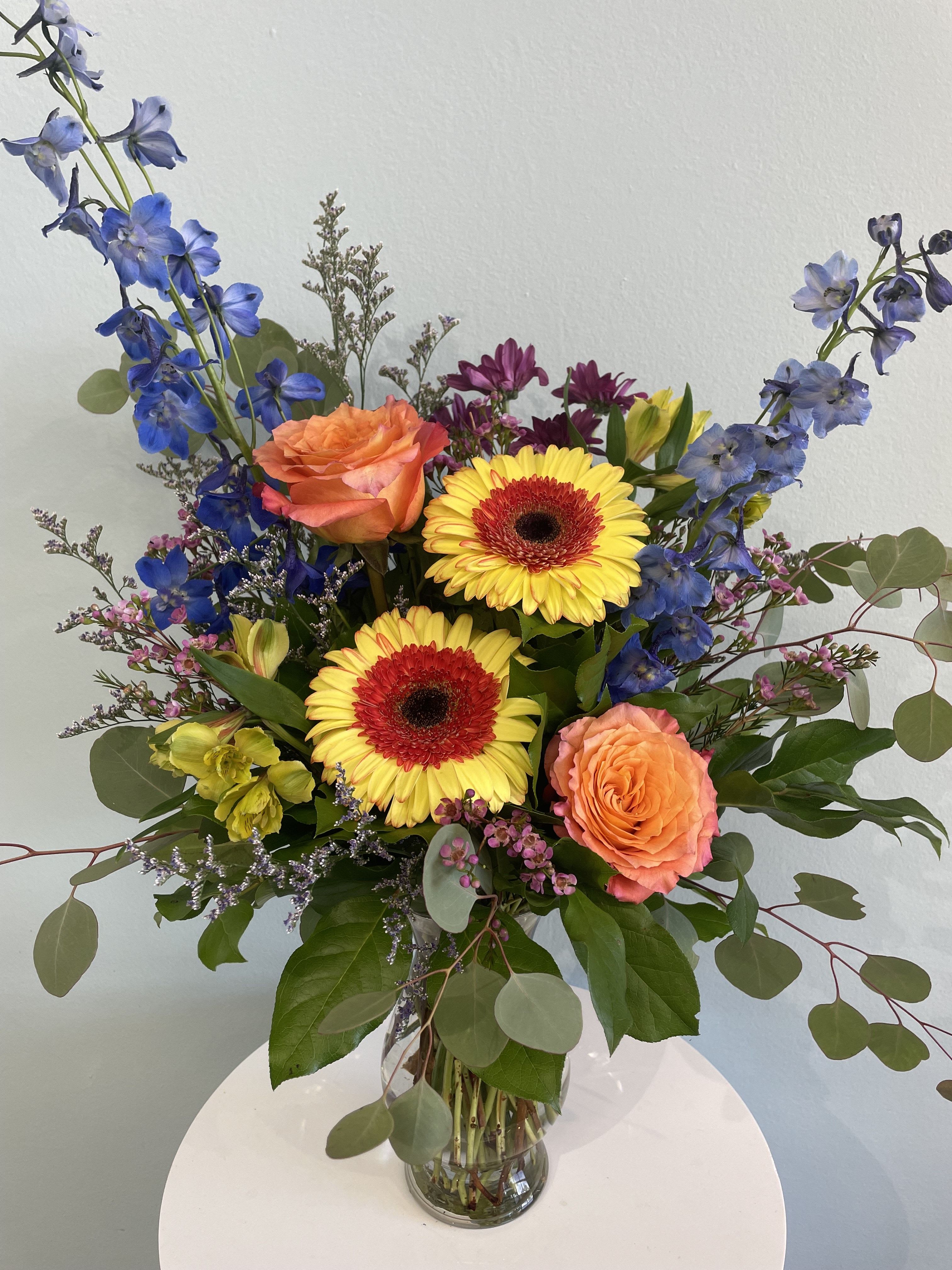 Colorado Sunset - Give your recipient the gift of Colorado with this stunning floral arrangement. This arrangement demonstrates the beauty of the Rocky Mountain State and may include colorful (Colorado) gerbera daisies, royal blue delphinium, and our beautiful free spirit roses. This arrangement comes in a simple yet classic vase with a mix of greenery.