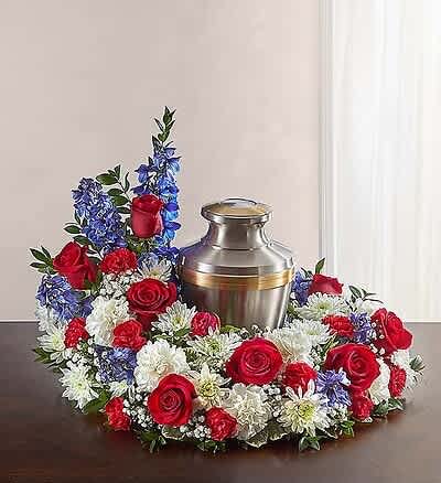 patriotic tribute ) Cremation Urn arrangement. - "Commemorate and honor your loved one through our Meaningful Memorial Urn arrangement. This arrangement includes  roses, delphinium, carnations and more. An urn or framed photograph can be placed in the open center, creating a fitting, patriotic tribute for the cremation or memorial service. 