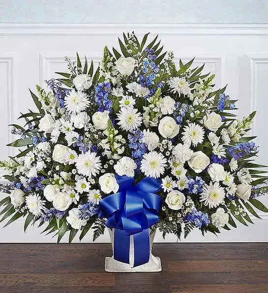 Heartfelt Tribute Blue &amp; White Floor Basket Arrangement - Offer the peace and tranquility that comes from classic blue and white flowers. Our elegant floor basket arrangement, handcrafted by our caring florists with pristine white and blue blooms, is a tasteful gesture perfectly suited for the funeral home or memorial services.Floor basket arrangement of blue delphinium; white roses, snapdragons, cremones, carnations, daisy poms and monte casino; accented with soft, lush greenery