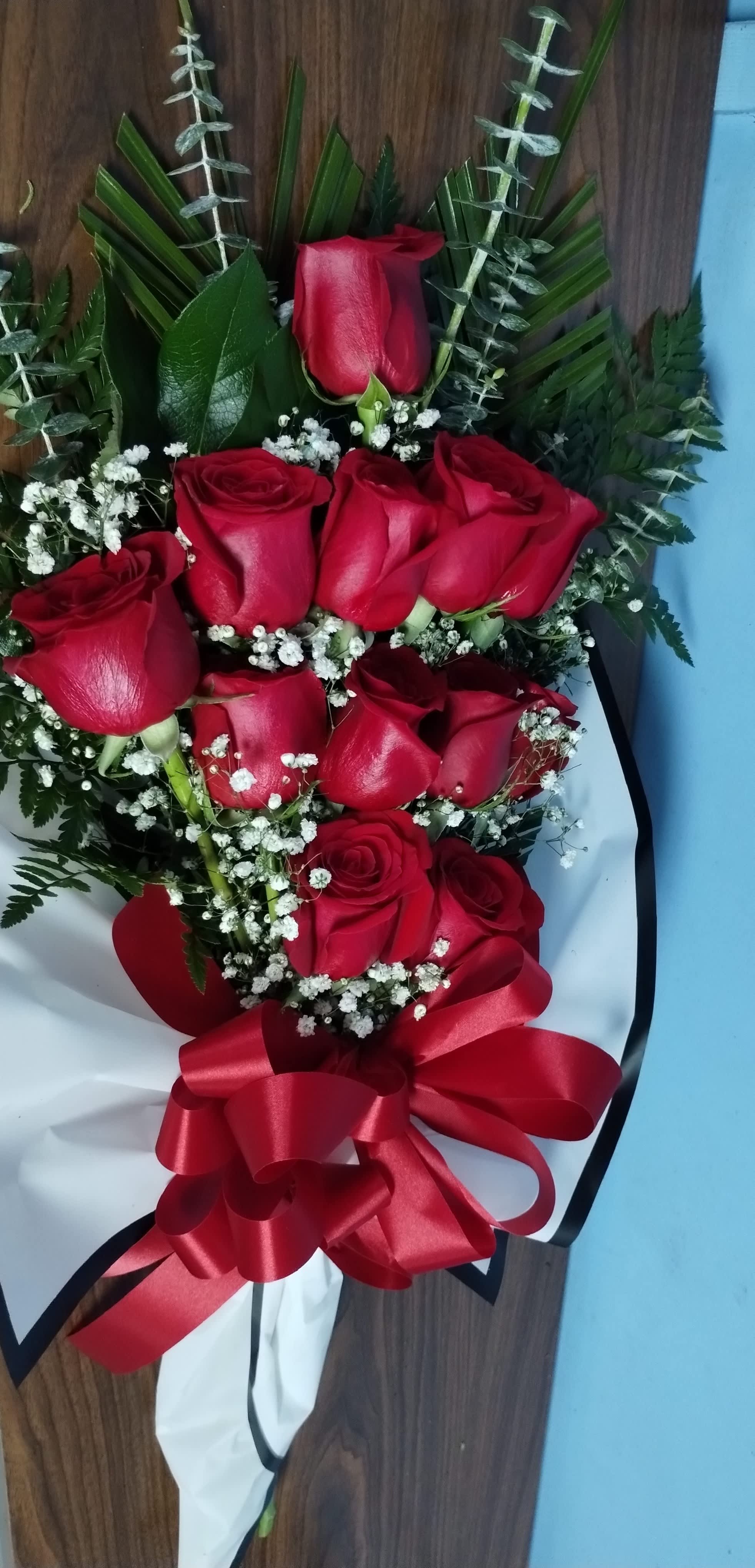 One Dozen Roses Wrapped Bouquet  - Great for Graduations. It is one dozen roses wrapped in a pretty wax paper tied with a bow and comes with fillers and greenery. For other colors, Call ahead, to check availability. This is for a limited time only and makes the perfect treat for that special someone. So place your order and we will have it ready for you to pick up.