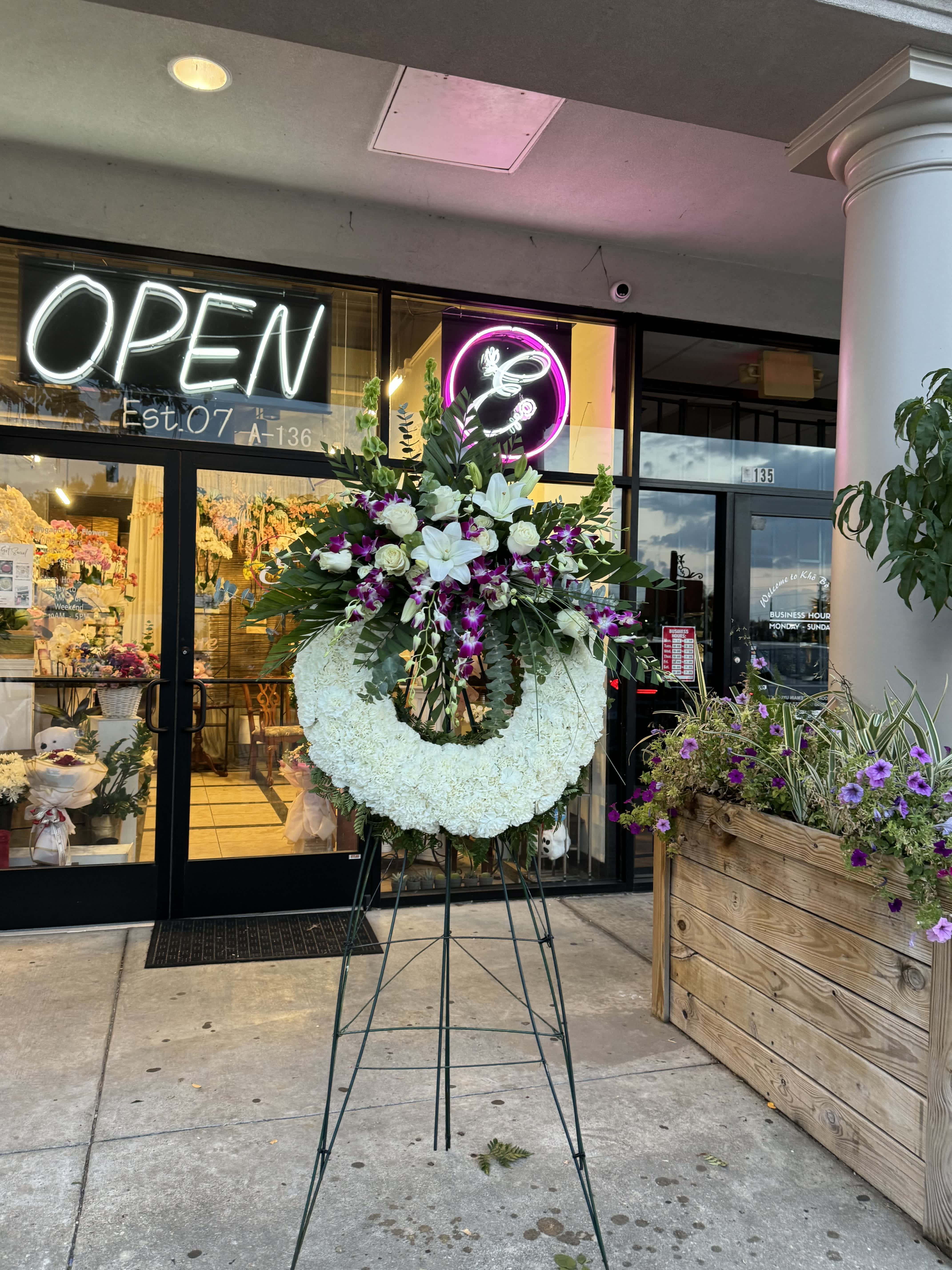 Wreath Stand #6 - A standing wreath is a circular floral arrangement, often used in funerals and memorial services. Its circular shape symbolizes eternal life, continuity, and the cyclical nature of life. Standing wreaths are crafted from a variety of flowers and greenery. They can be customized with ribbons, sashes, or personalized messages, offering a poignant tribute to the deceased and expressing condolences and remembrance.