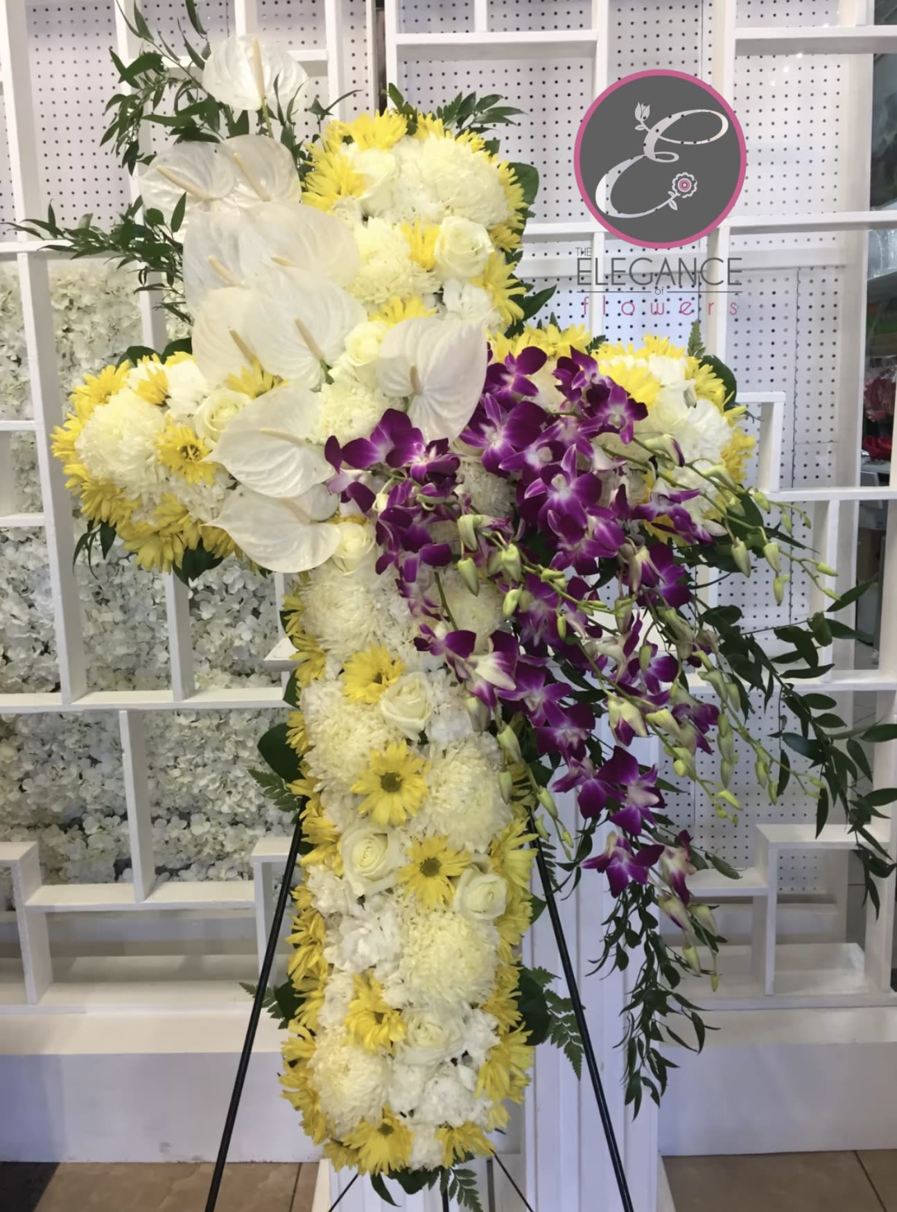 Cross Stand #12 - The cross stand for a funeral is a graceful tribute, symbolizing faith and remembrance. Adorned with fresh flowers, it stands as a comforting centerpiece during memorial services.
