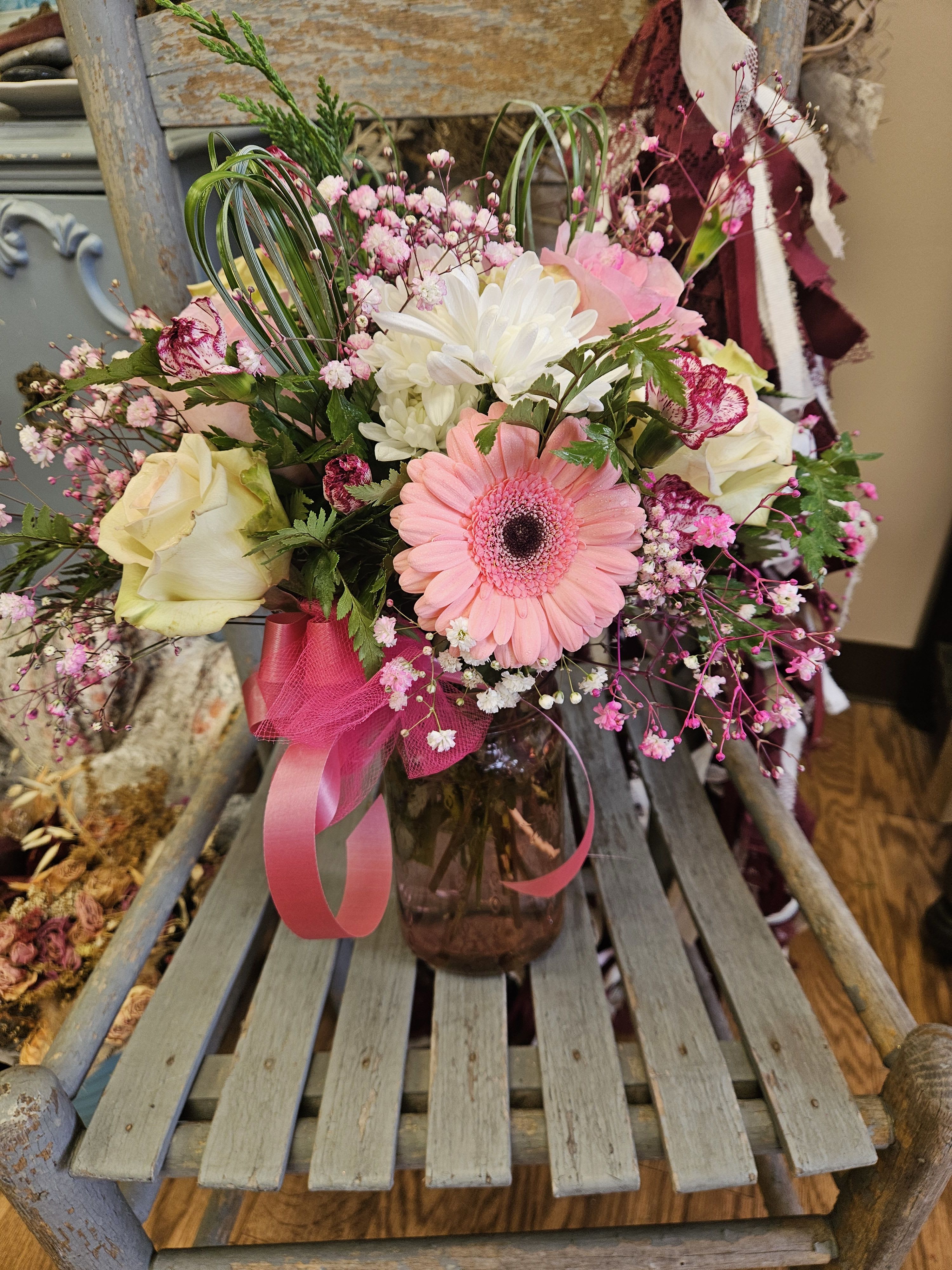 Pretty Lady - Perfect for the pretty lady in your life! Varying shades of pink roses, purple and white mini carnations, white cushion mums, and pink gerbera daisies in a pink vase. 