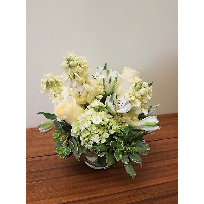 Cream Beauty - Delicate arrangement of cream roses, light yellow stock, mini green hydrangea, white alstroemeria arranged in short vase. Great for a centerpiece 