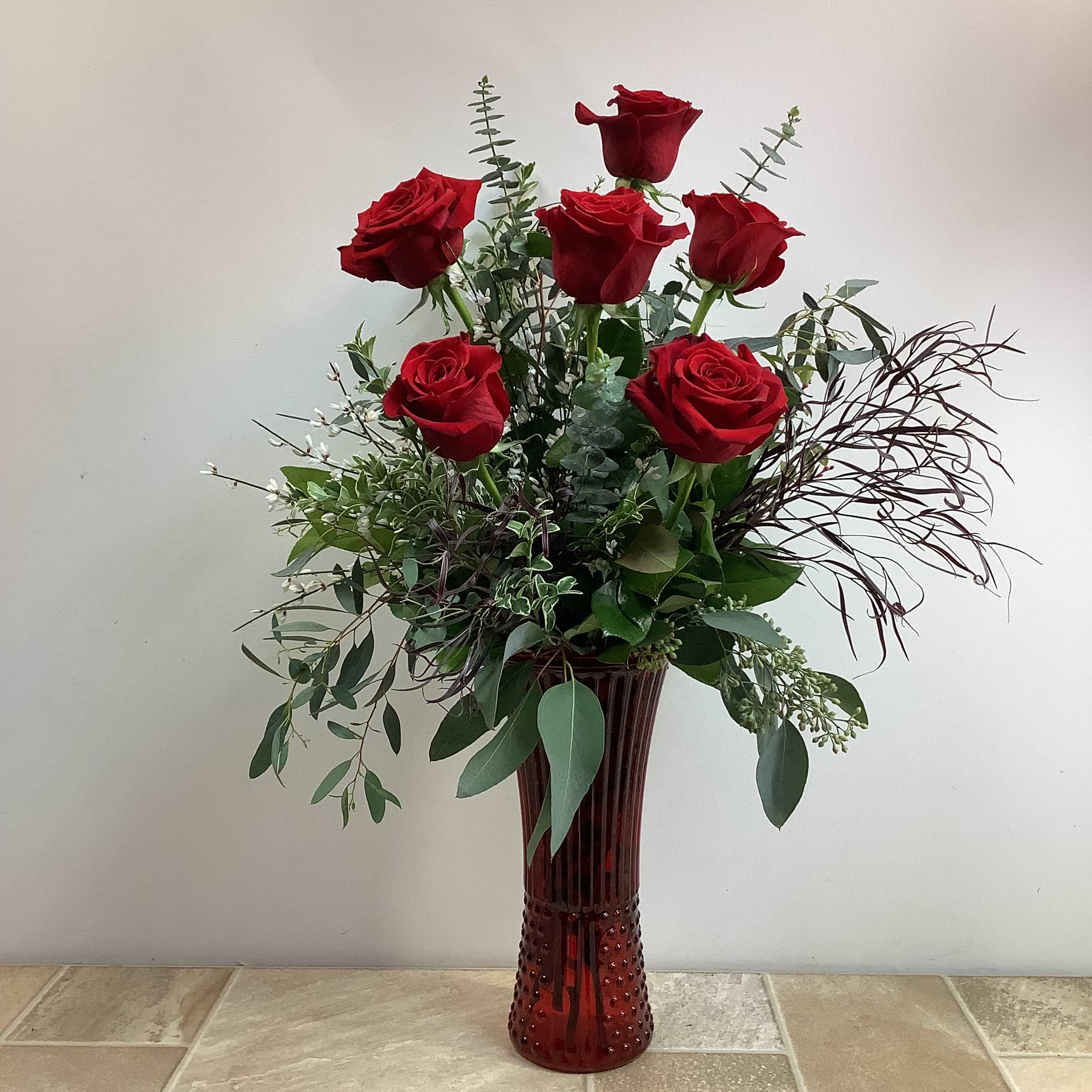 Red Rose Elegance  - You can't go wrong with this premium bouquet of six of our finest long stemmed red roses arranged in a beautiful ruby red glass vase. Assorted greens add texture and fullness. Approximate size: 13” wide x 26” tall.  Primary flowers: rose