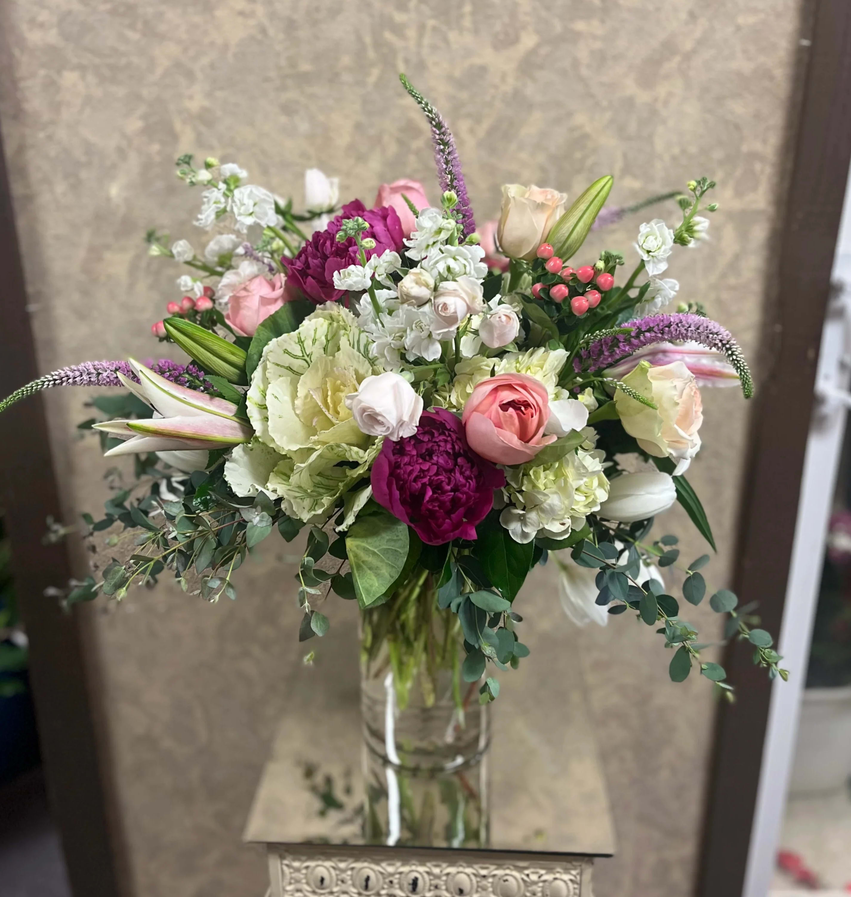 Love Her Madly - Type of Flowers: Pink peonies, Coral Roses, Pink Roses, Pink Spray Roses, Hypericum Berries, White Stock, White Tulips, White Hydrangeas, Stargazer Lilies, and more in a tall, clear vase. Availability: All year round Design View: Symmetric Front Facing View Photo shown: Standard 