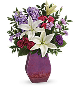  Regal Blossoms Bouque -  This bouquet includes hot pink spray roses, white asiatic lilies, purple carnations, lavender stock, huckleberry, and lemon leaf. Delivered in a Regal Blossoms vase. Approximately 15 3/4" W x 20 1/2" H 