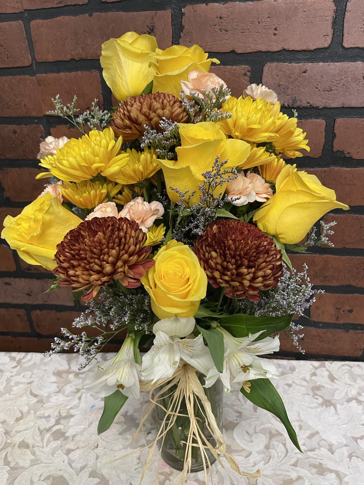 A Splash of Fall - This new Fall seasonal arrangement is just in time for the Autumn colors seen around us.  You will get beautiful &amp; bold yellow roses with chrysanthemums, alstromerias &amp; carnations in a clear vase embillished with a raffia ribbon.