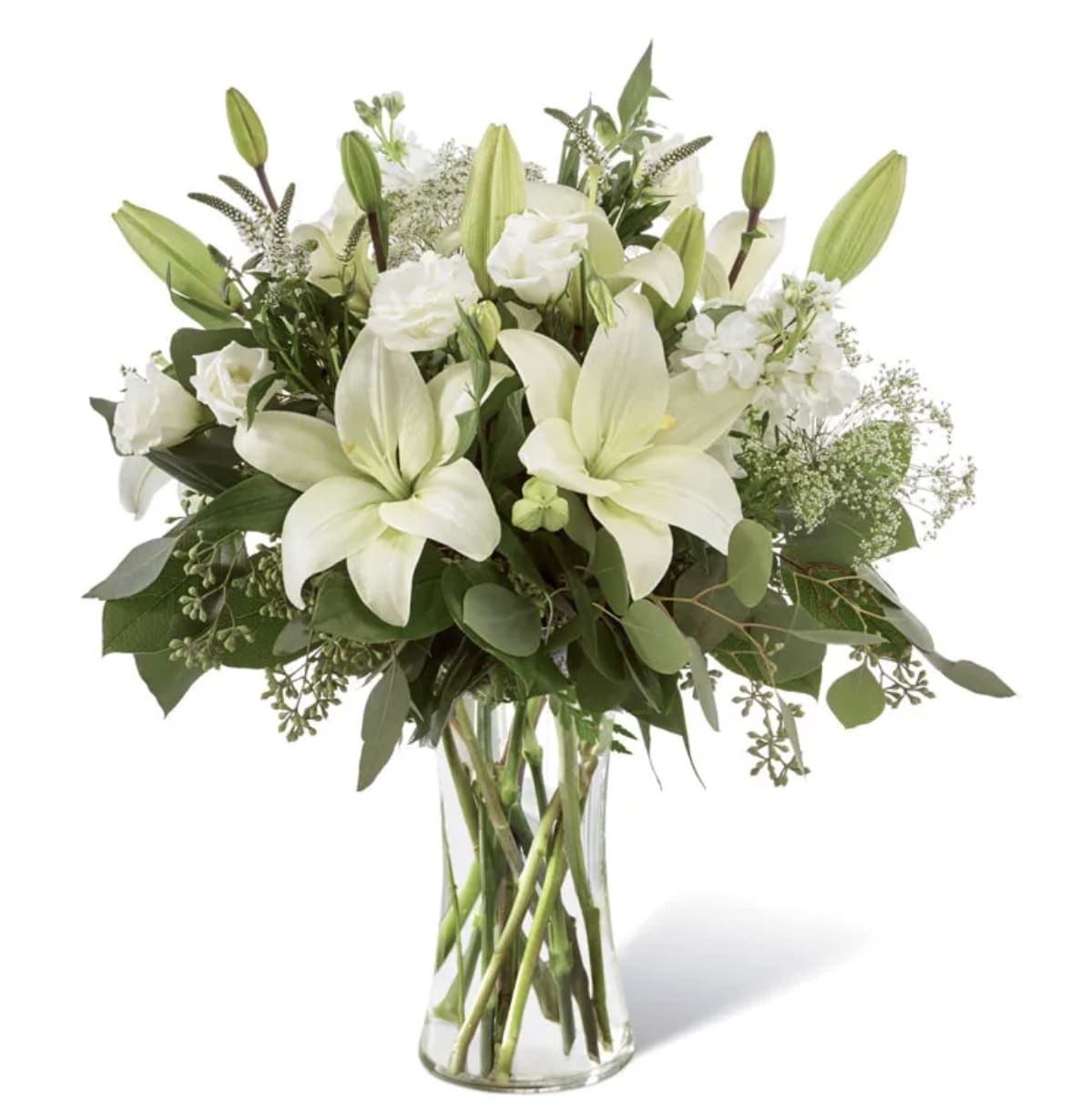 Enchanting Arrangement - This striking array of ivory and green within a clear textured glass vase. Handcrafted using Asiatic lilies interwoven with white Veronica, white stock, Queen Anne's lace, silver dollar eucalyptus and seeded eucalyptus, this bouquet graces every room with a touch of elegance.  Includes: • White Lilies • White Lisianthus • White Stock • Queen Anne's Lace • White Veronica • Eucalyptus